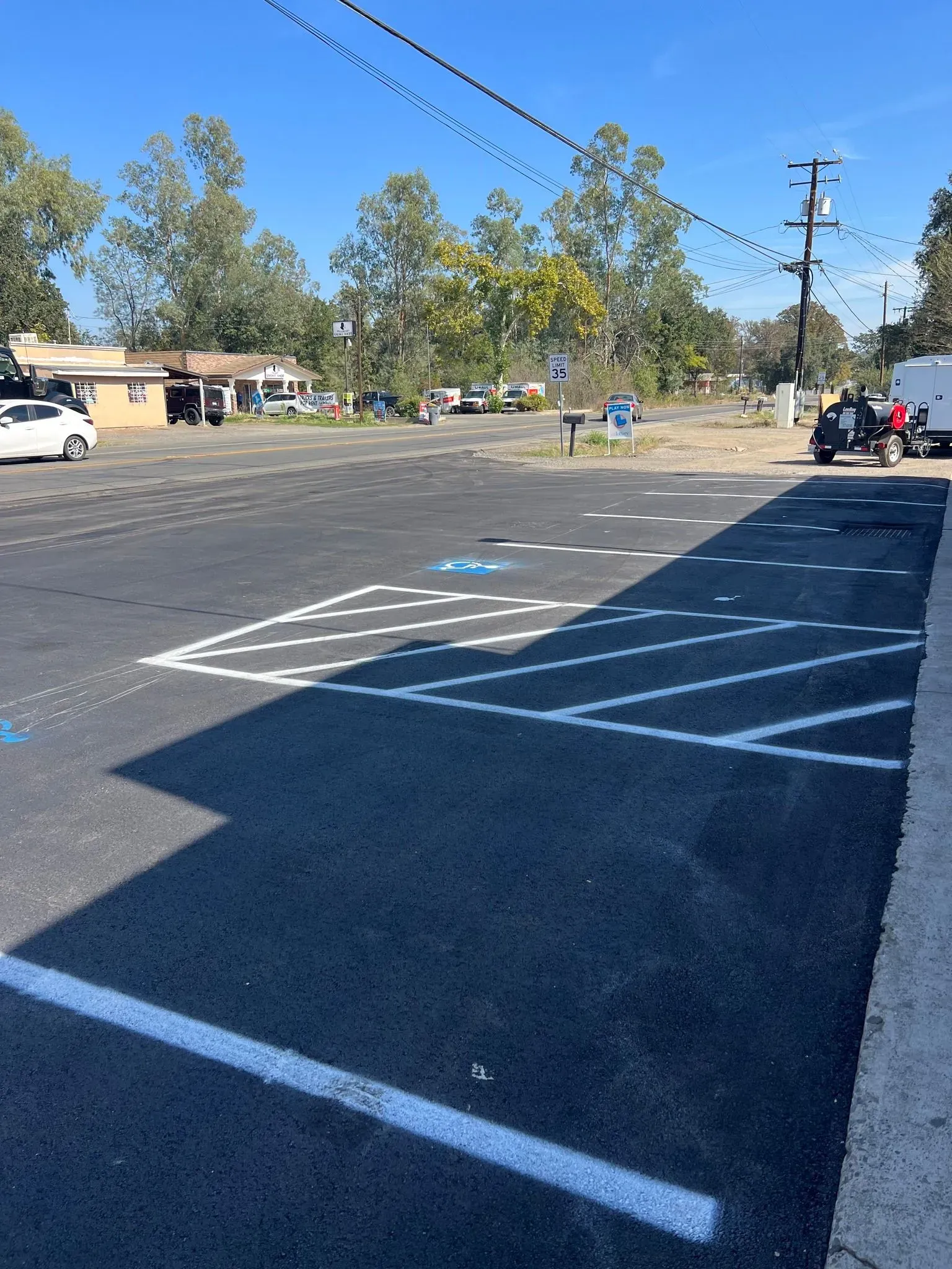 Asphalt parking lot with painted white and blue parking lines under a bright sky.