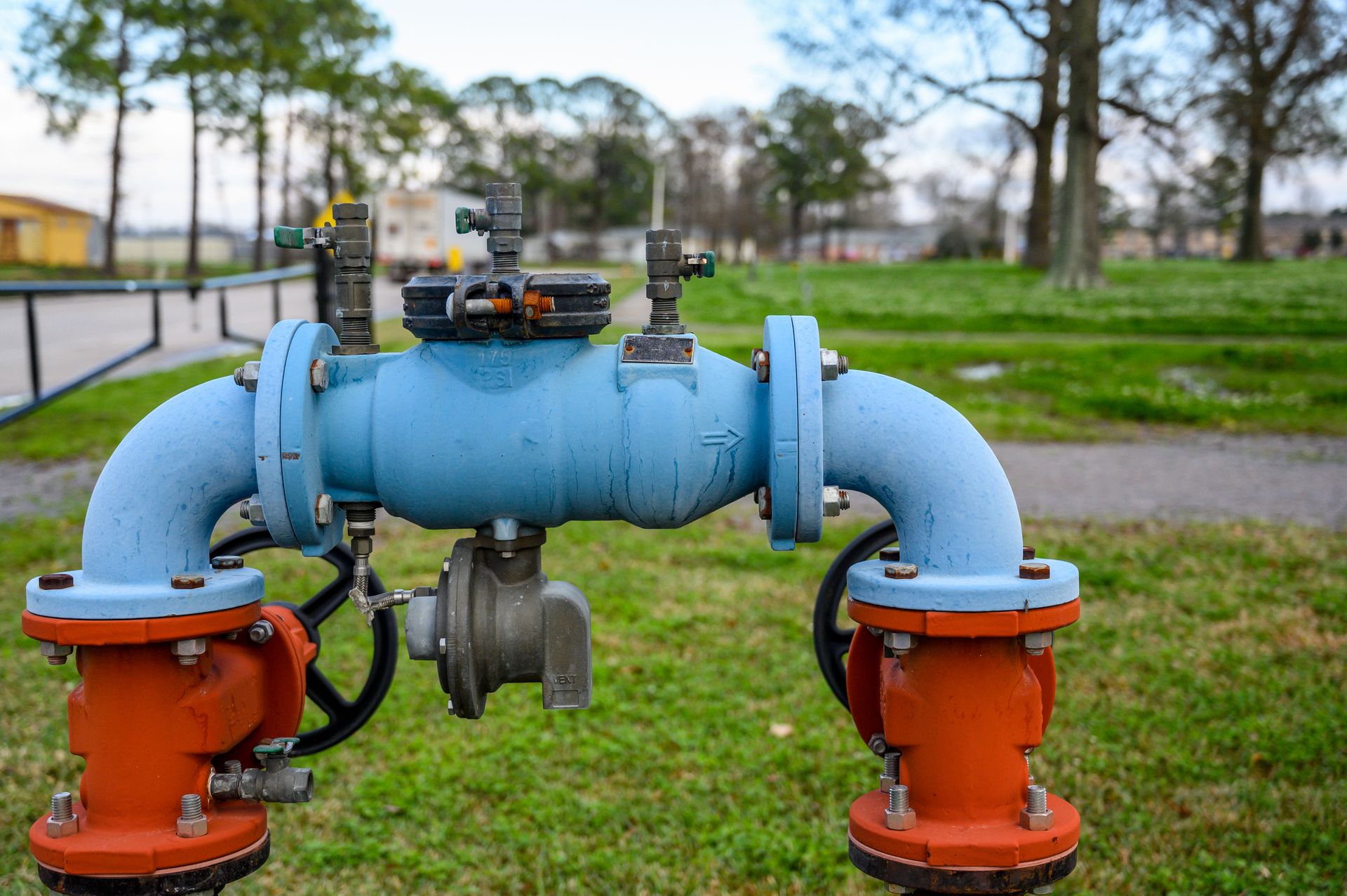 A close up of a blue and orange water pipe in a park.
