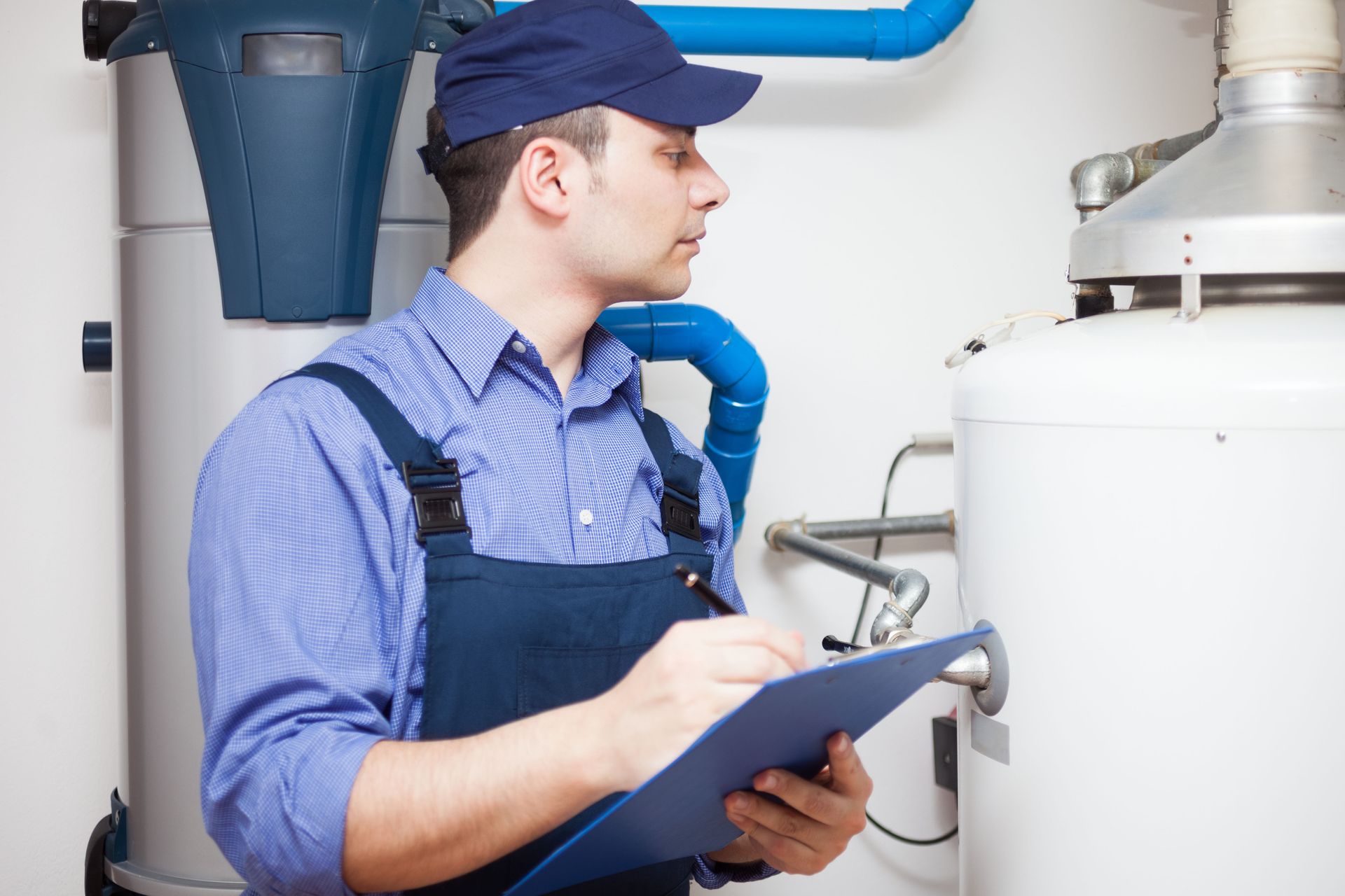 A man is holding a clipboard in front of a water heater.