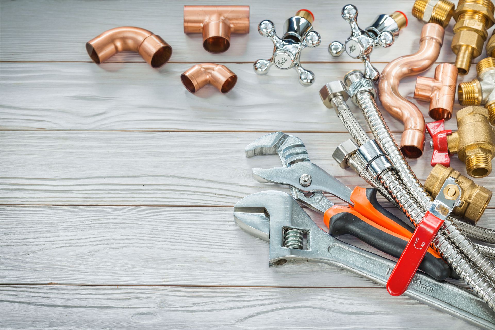 A bunch of plumbing pipes and tools on a wooden table.