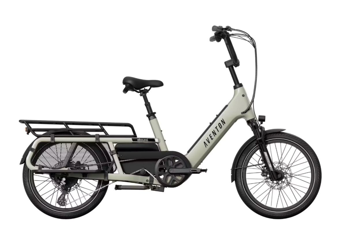 Side view of a gray electric cargo bike with rear rack and black wheels on a white background