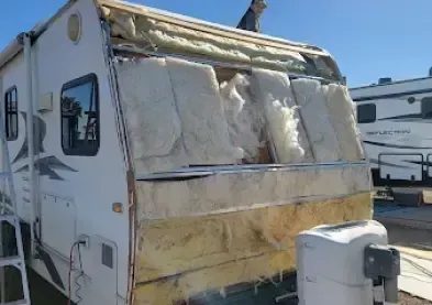 RV with roof and wall removed, revealing insulation. A person works on top.