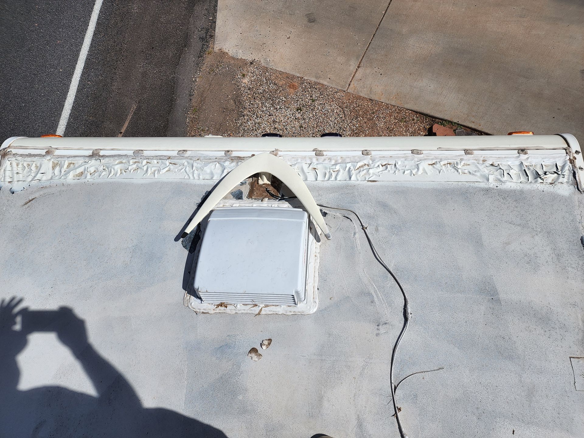 Overhead view of an RV roof showing a vent, decorative trim, and asphalt roof.