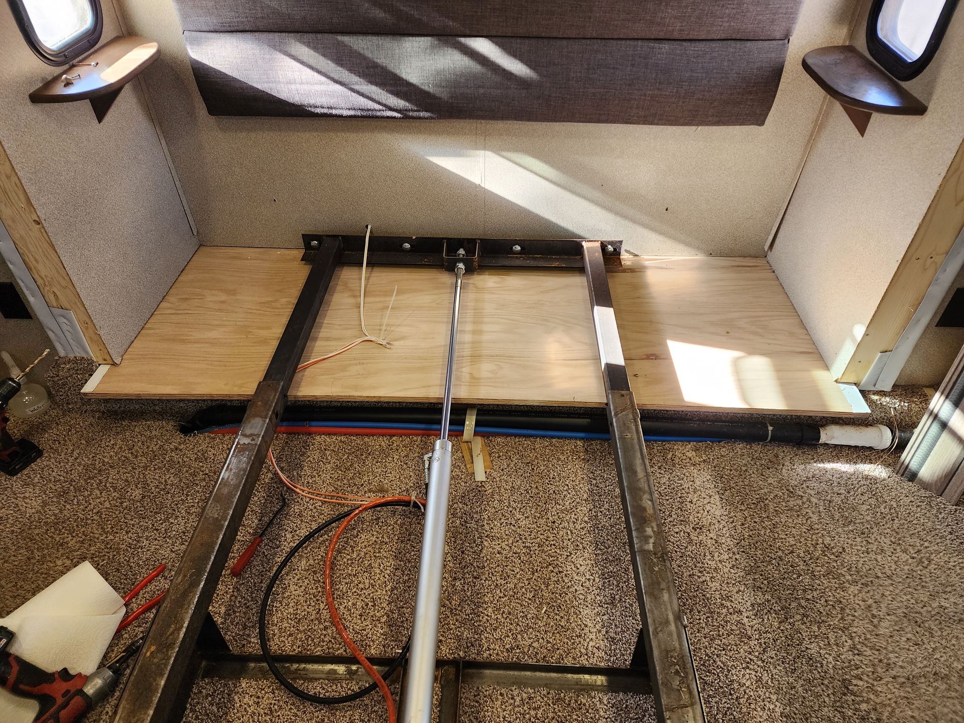 RV bed frame under construction with plywood and metal supports.