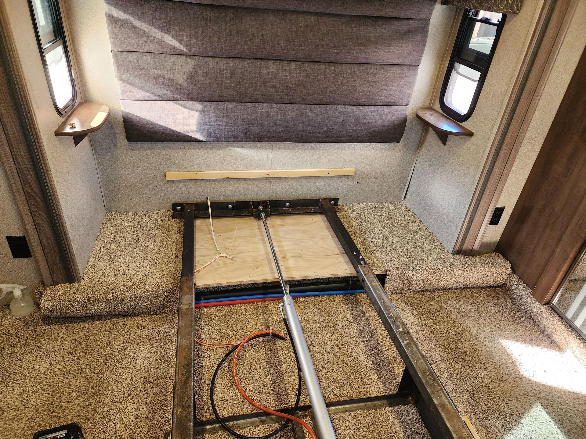 RV bedroom with metal frame bed base. Brown carpet and neutral walls. Bed is partially disassembled.
