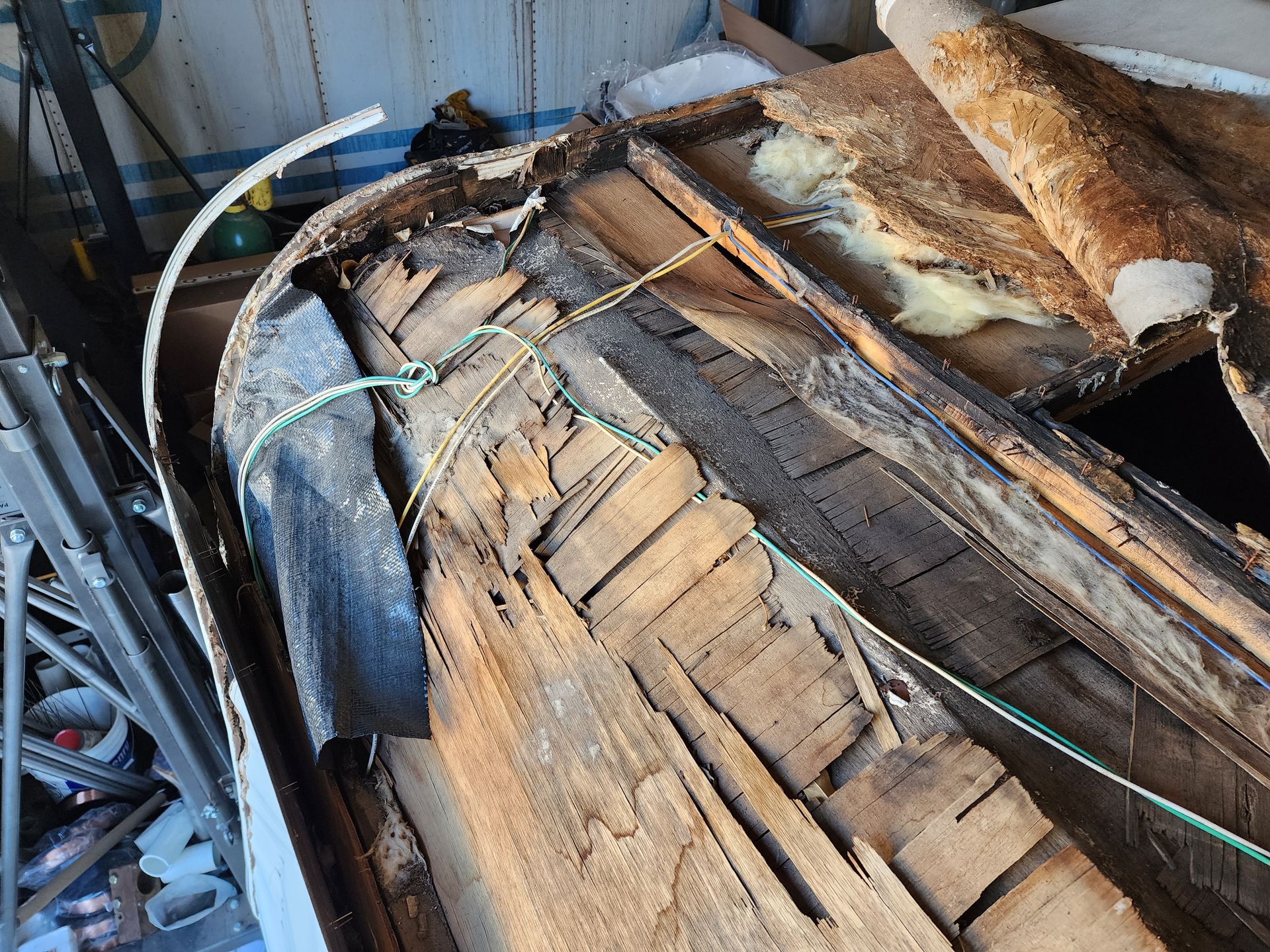 Damaged boat hull with rotted wood, showing exposed interior framing.
