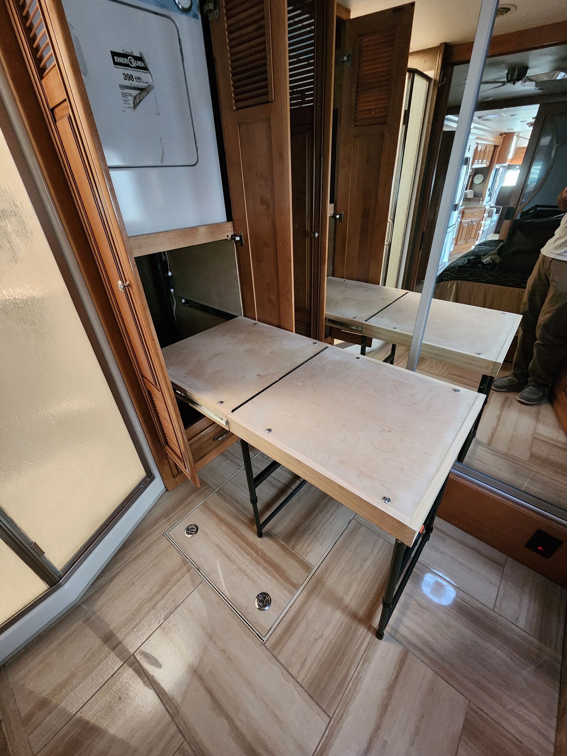 Foldable table set up inside a recreational vehicle. Beige wood tones and black metal legs.