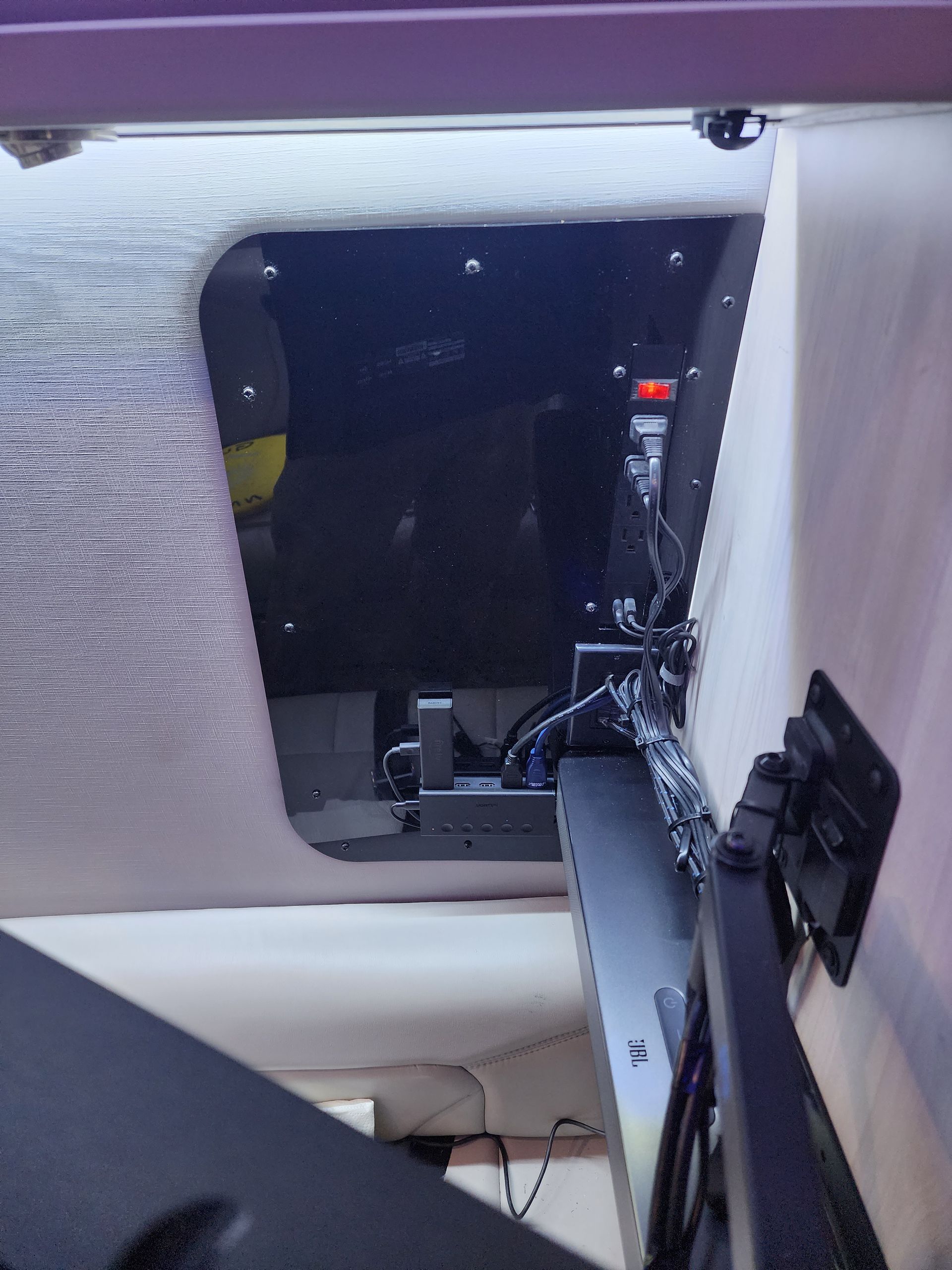 Overhead view inside a vehicle. A monitor is mounted to a wall. Wires are visible, and dark space can be seen.
