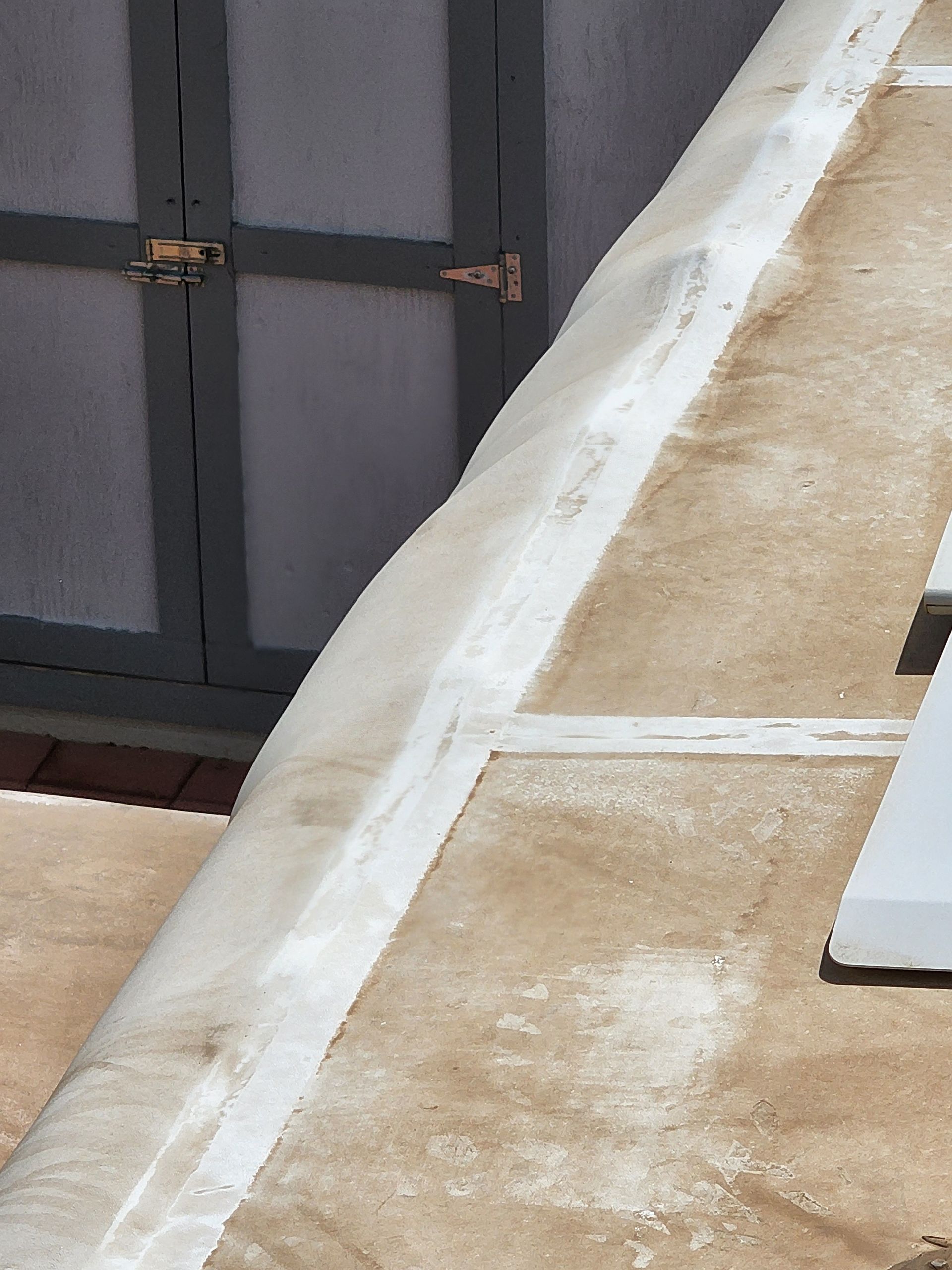 White concrete edge of a building with a gray door in the background.