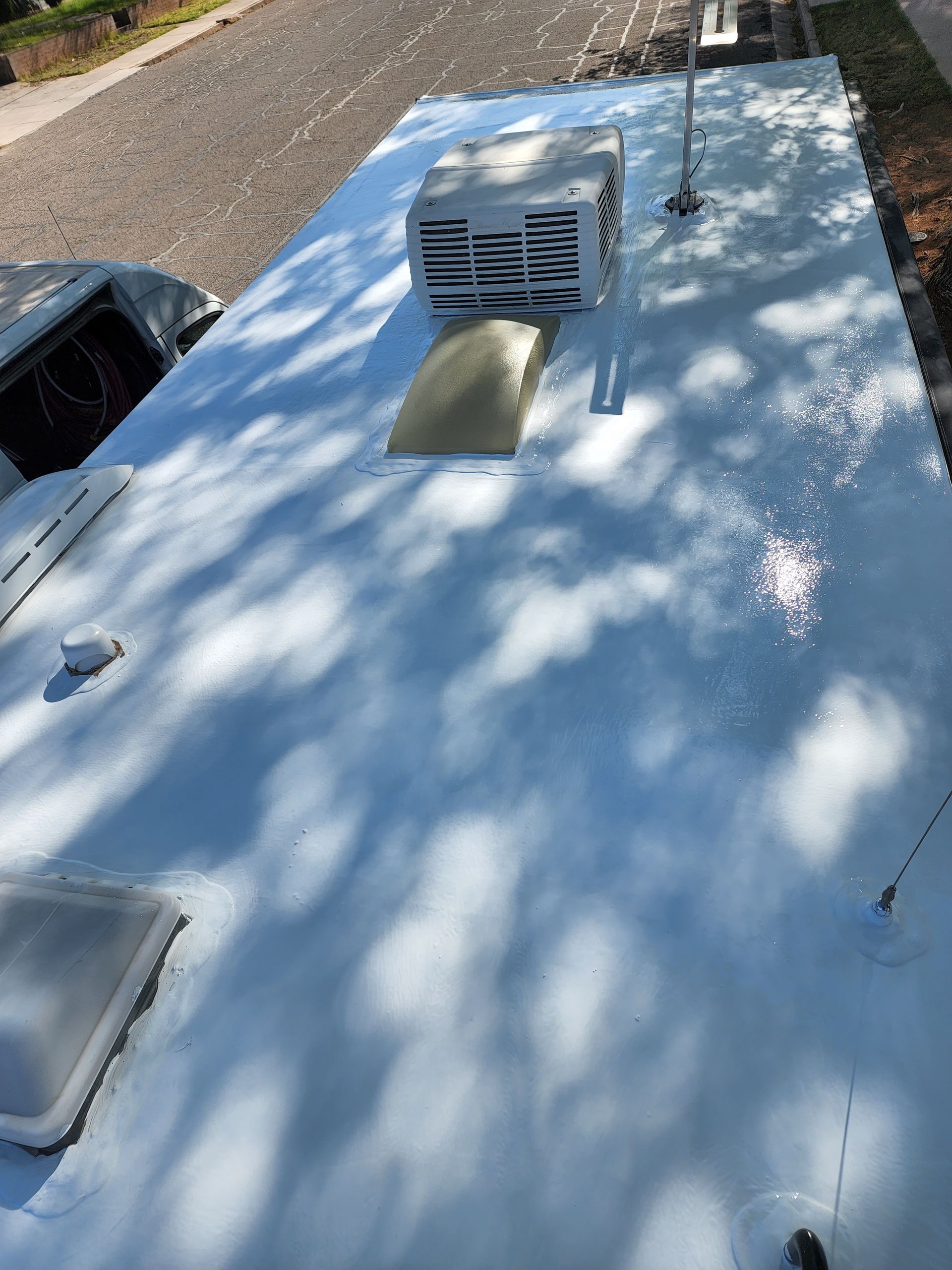 White RV roof with air conditioner, vent, and accessories.