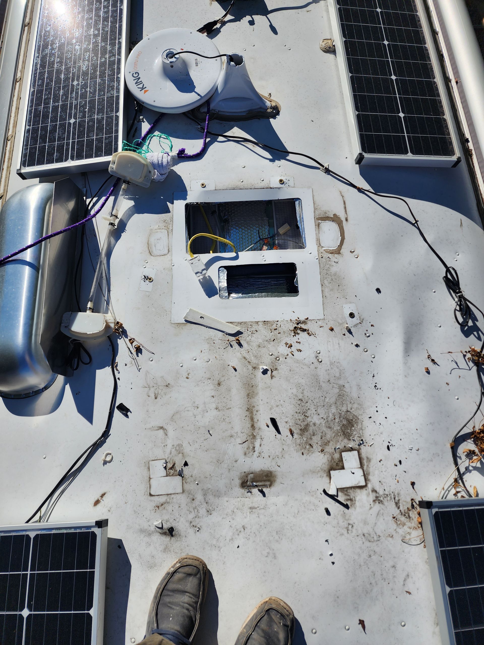 RV roof with damaged vent, solar panels, and wiring.