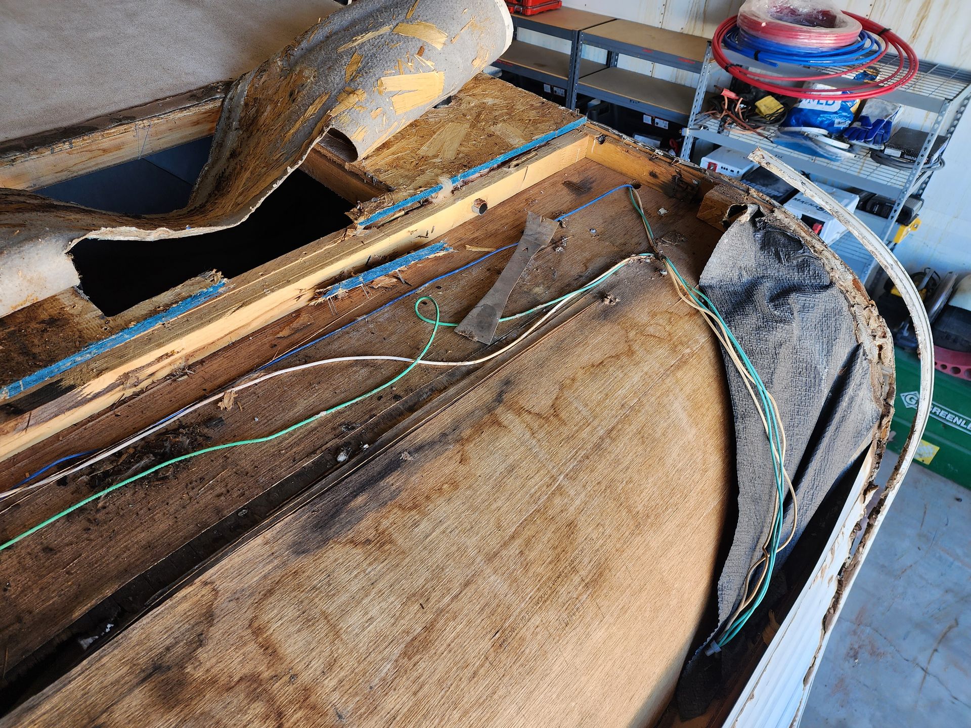 Damaged boat roof with exposed wood, wires, and detached material.