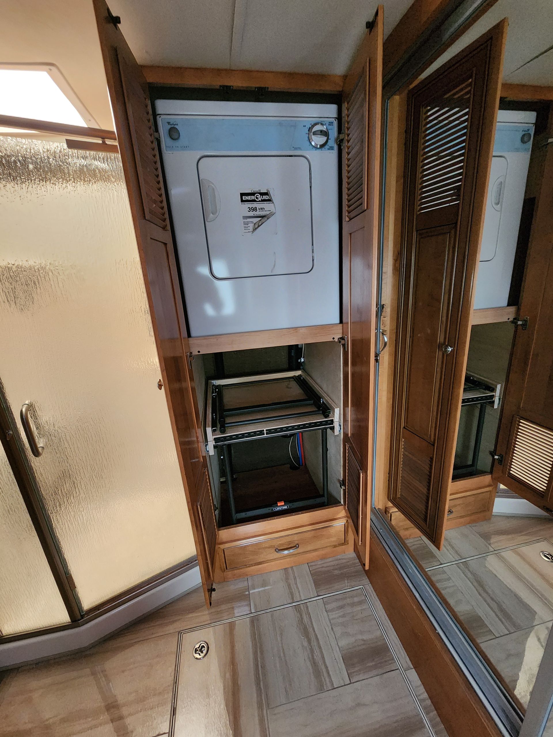 A built-in washer/dryer unit in a wooden cabinet, bathroom setting with mirrored doors.