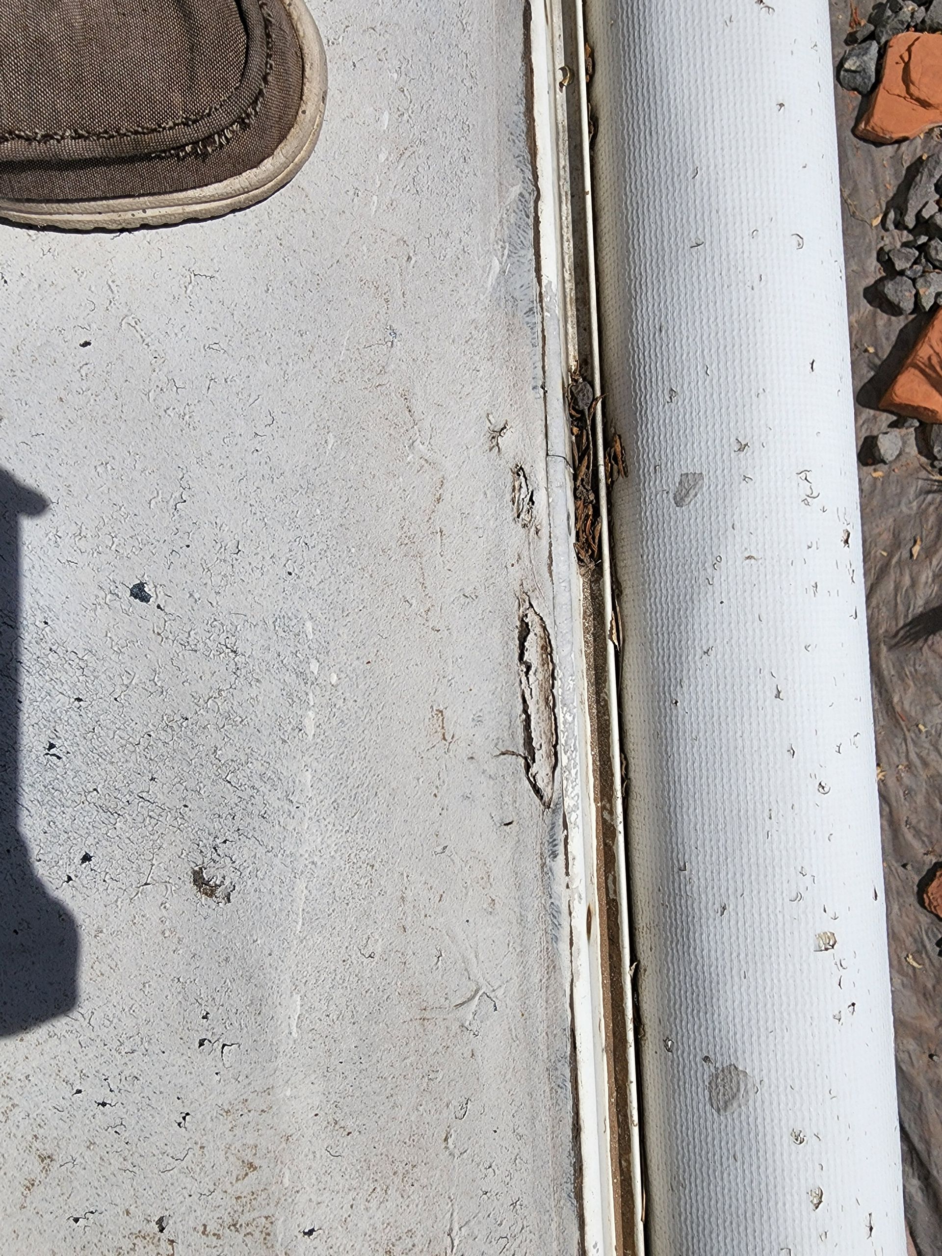 White concrete surface with a brown mat and white edging, showing wear and tear.