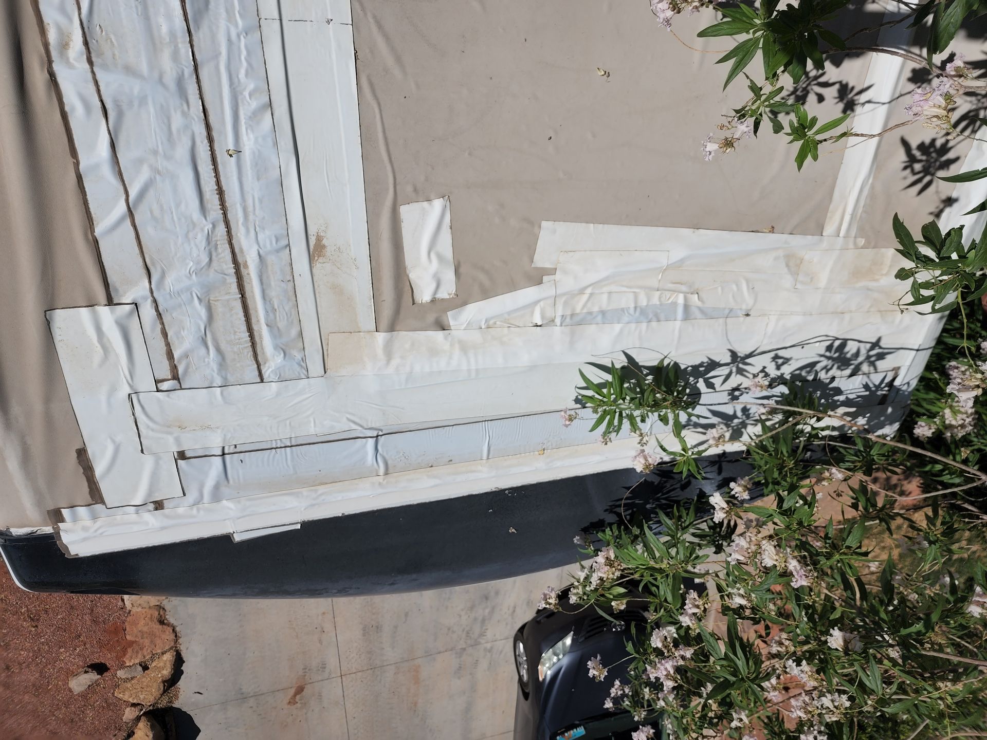 White fabric strips laid on a tan surface next to a black object and greenery.