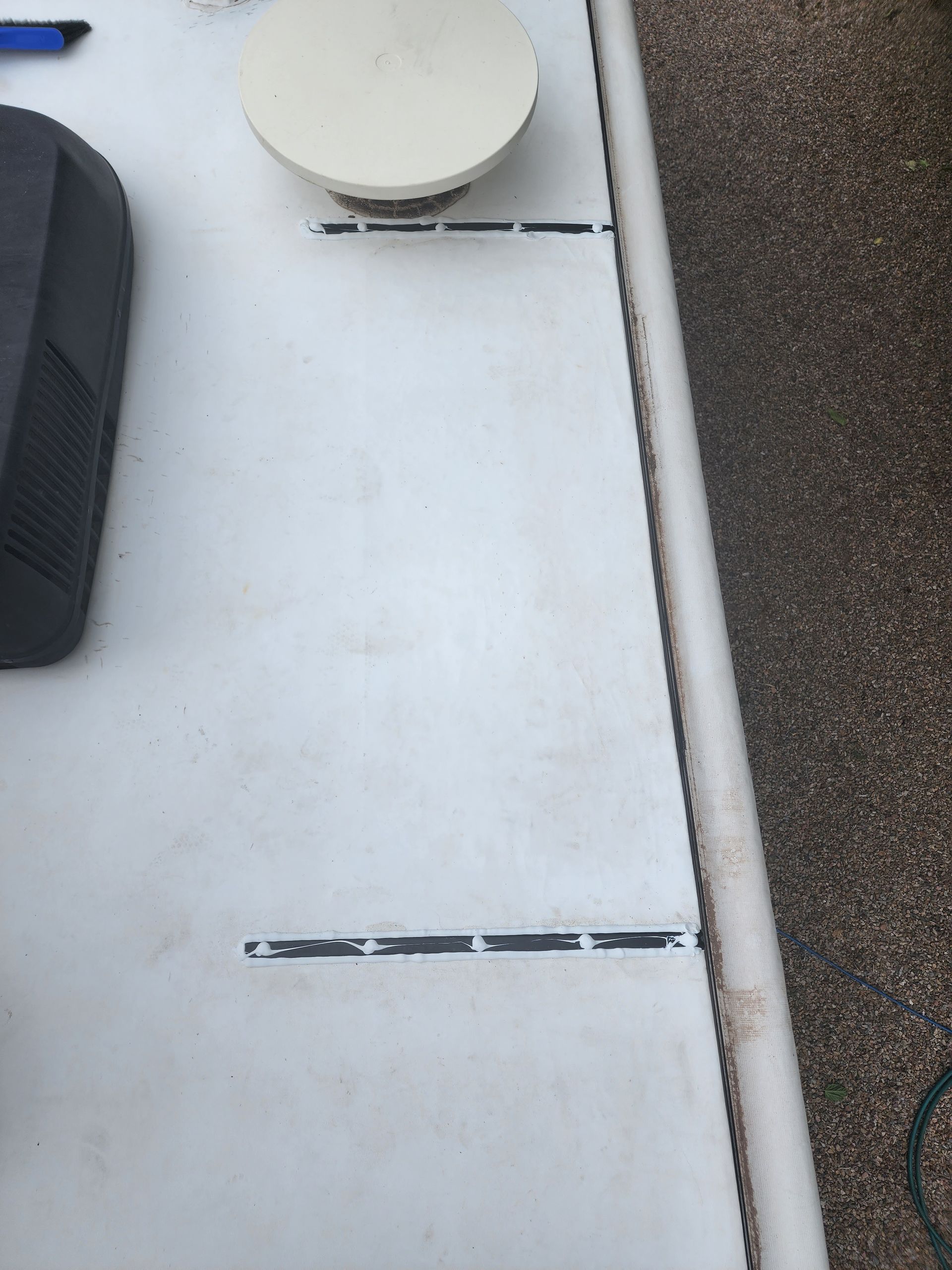 White RV roof with black markings, a white dome, and a black box.