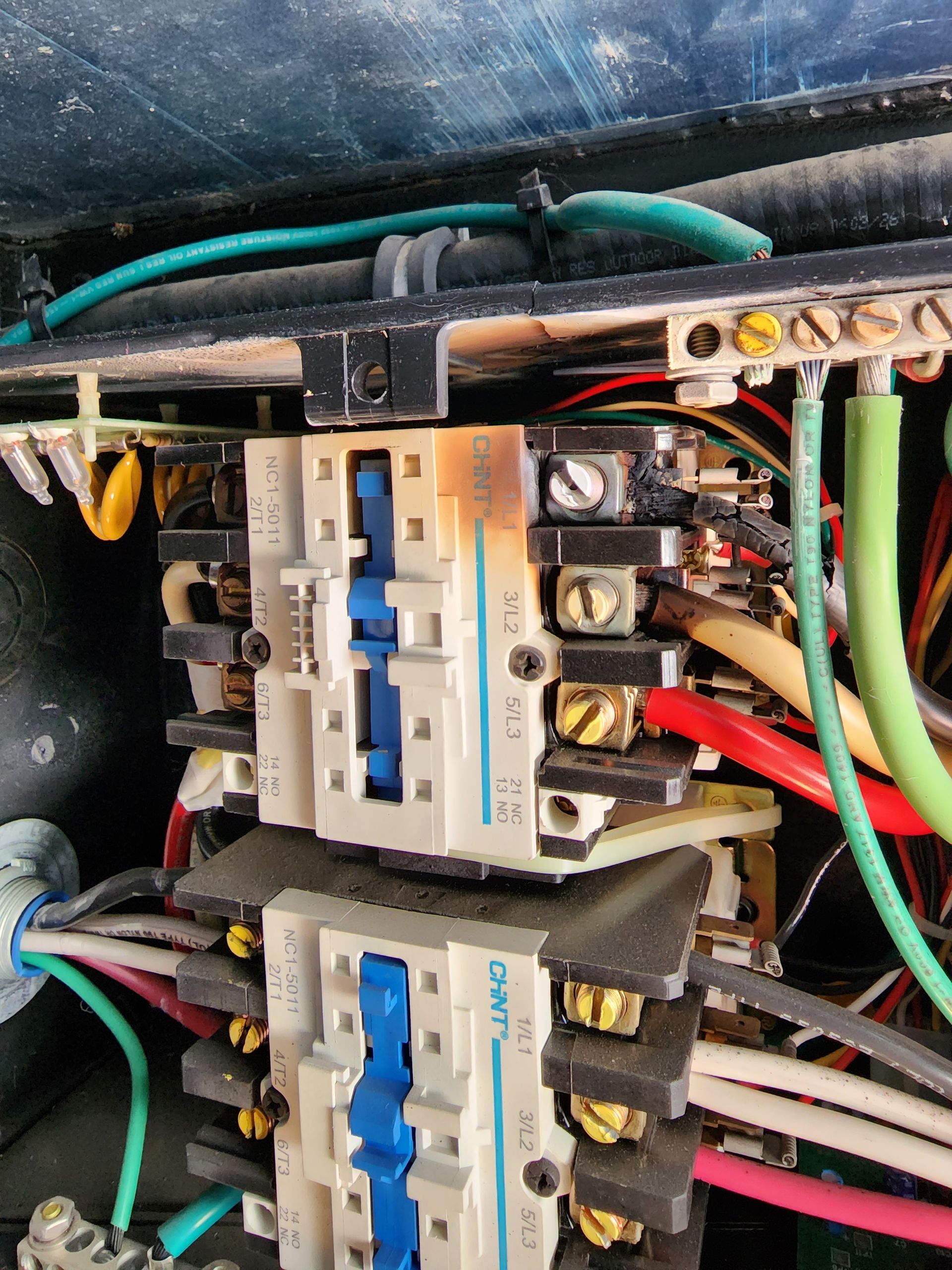 Burnt electrical circuit breakers in a panel with multiple wires, indicating a possible electrical fault.