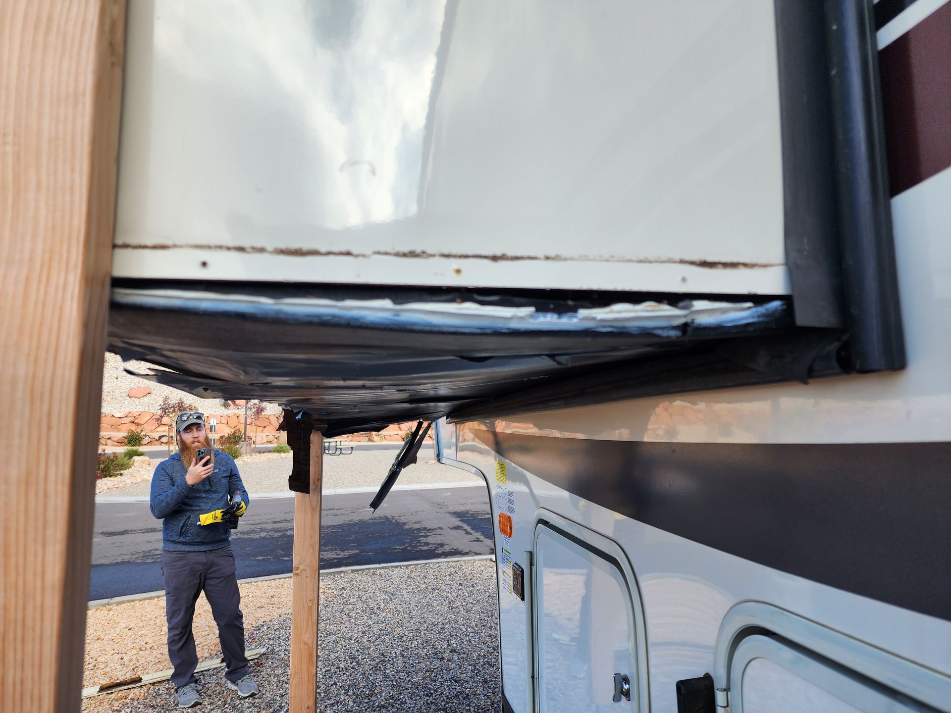 RV slide-out damaged with a man standing nearby in a campground.