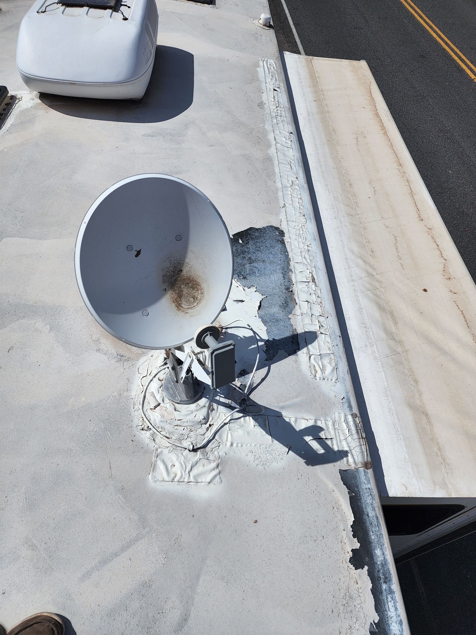 A satellite dish mounted on the white roof of an RV.