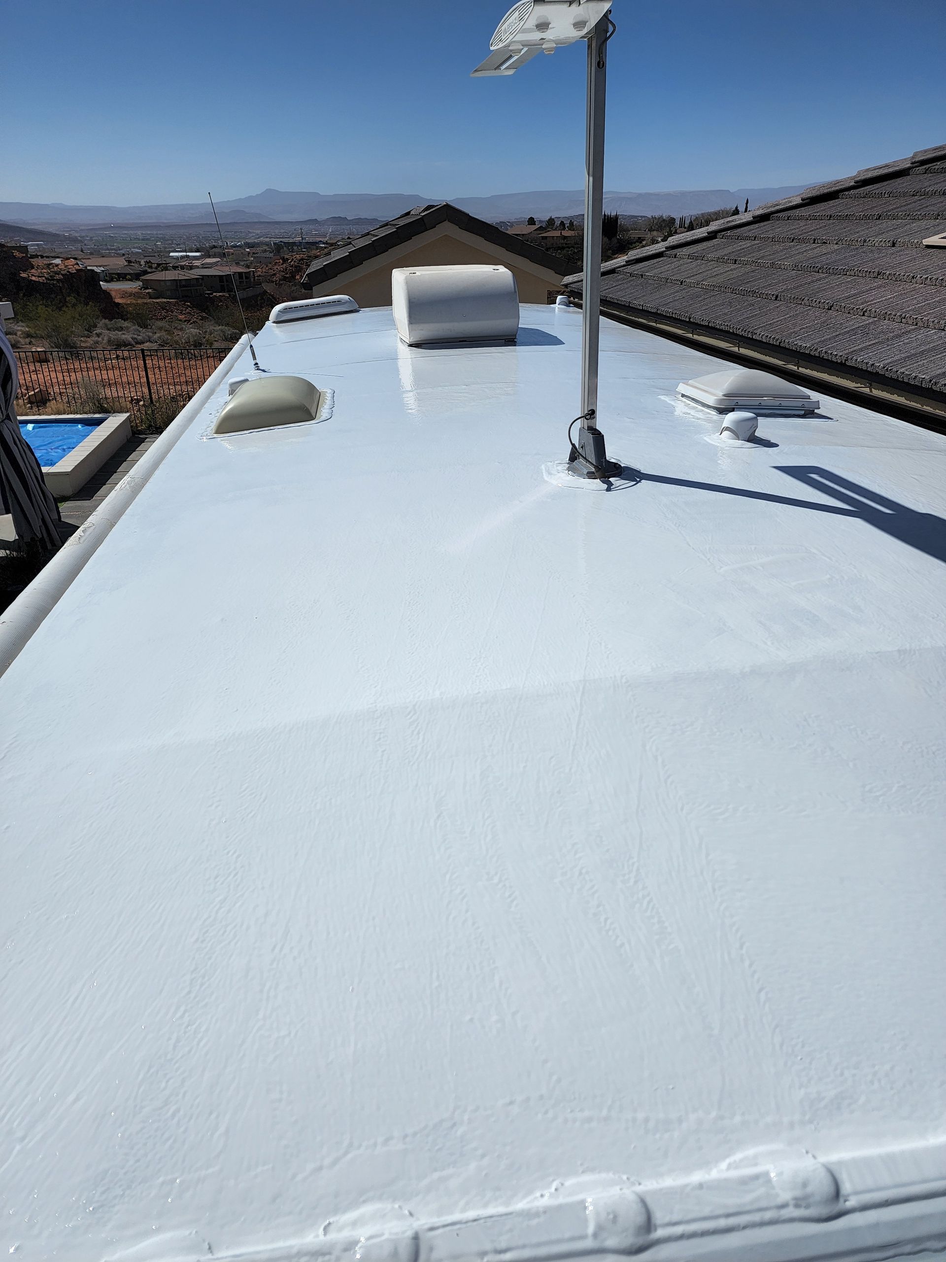 White RV roof with vents and antenna under a blue sky.