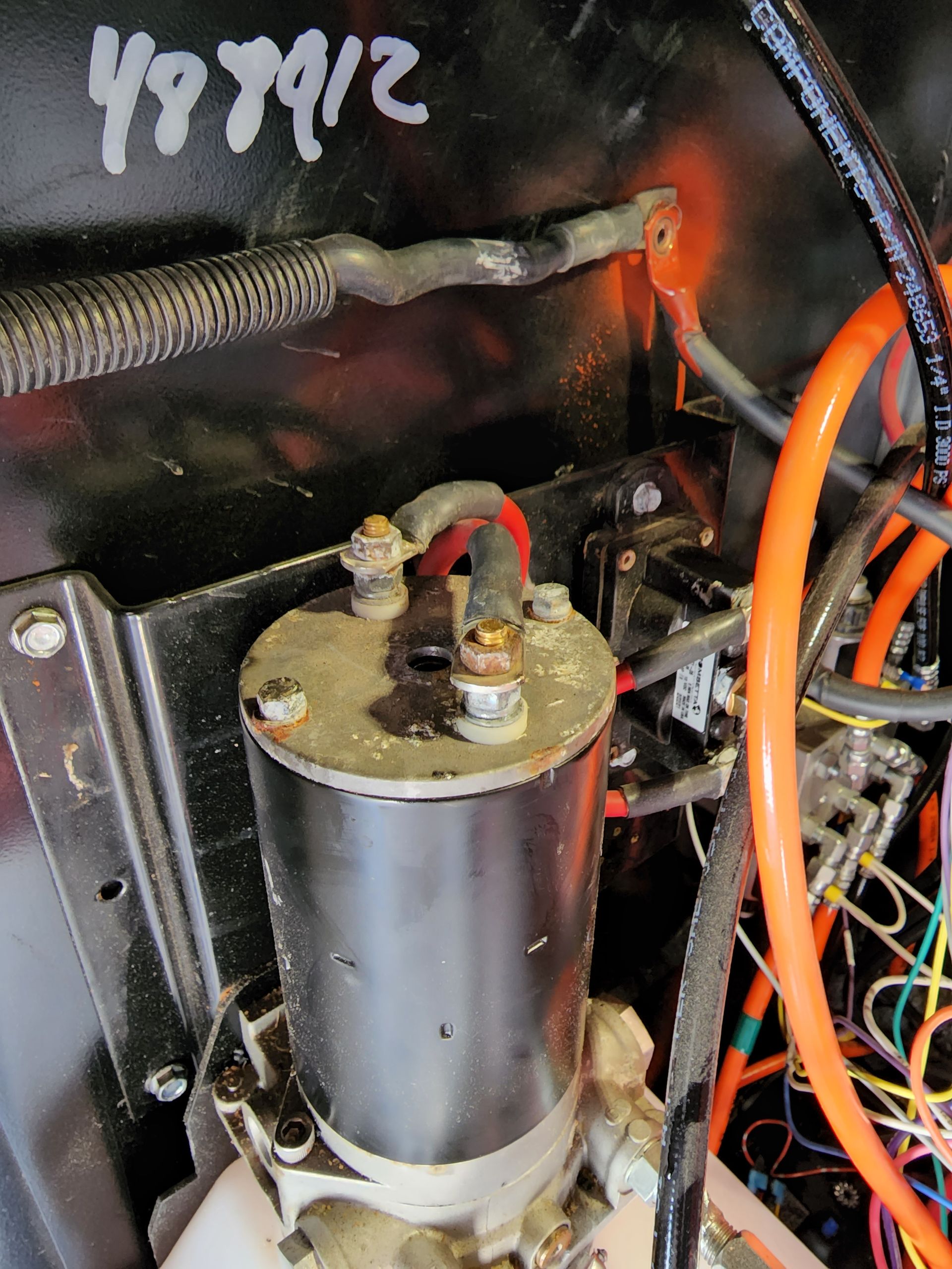 Close-up of a black electric motor with wiring; mounted in a dark enclosure with orange and black wires.