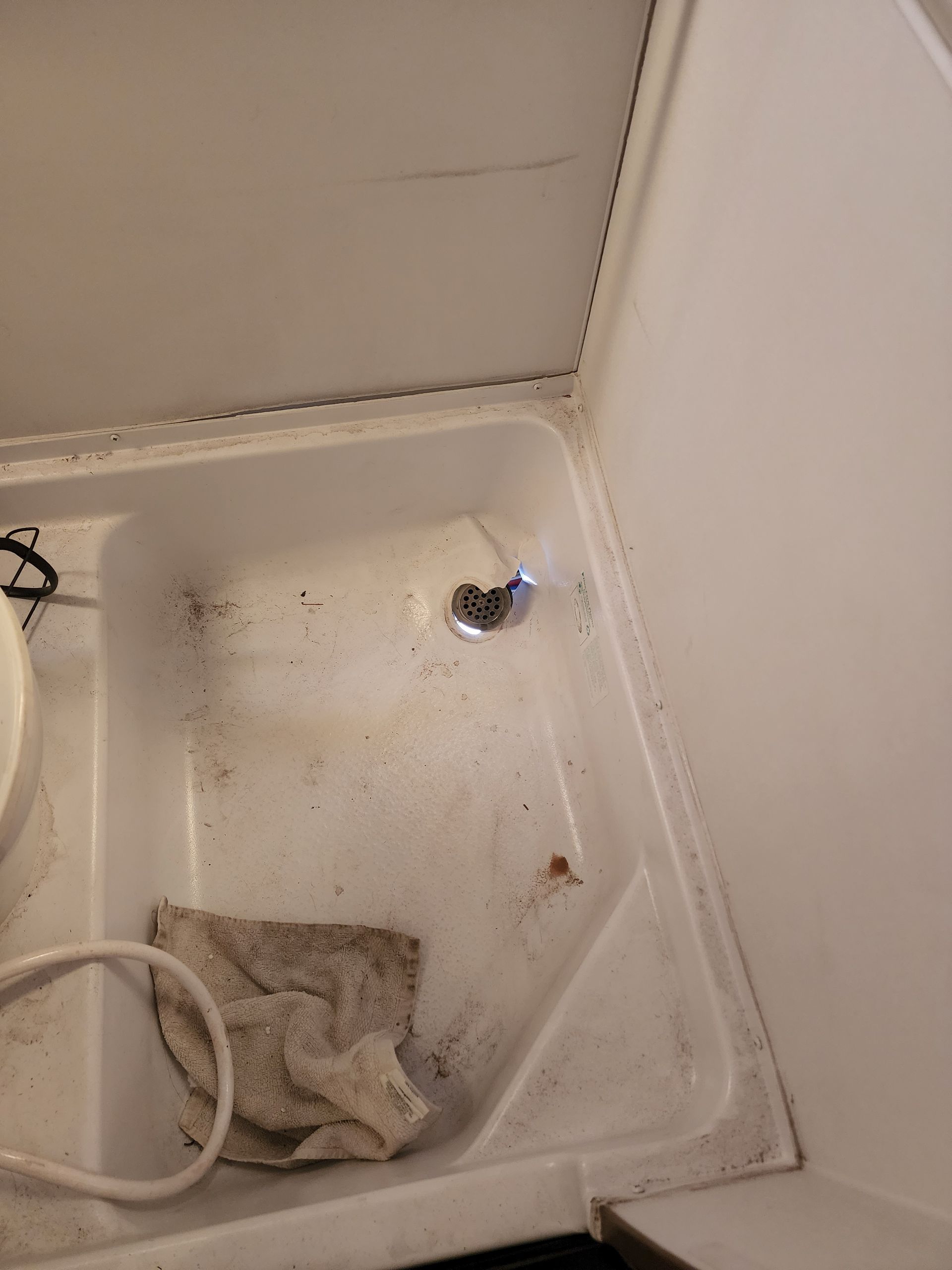 Dirty RV shower with shower head and cloth.