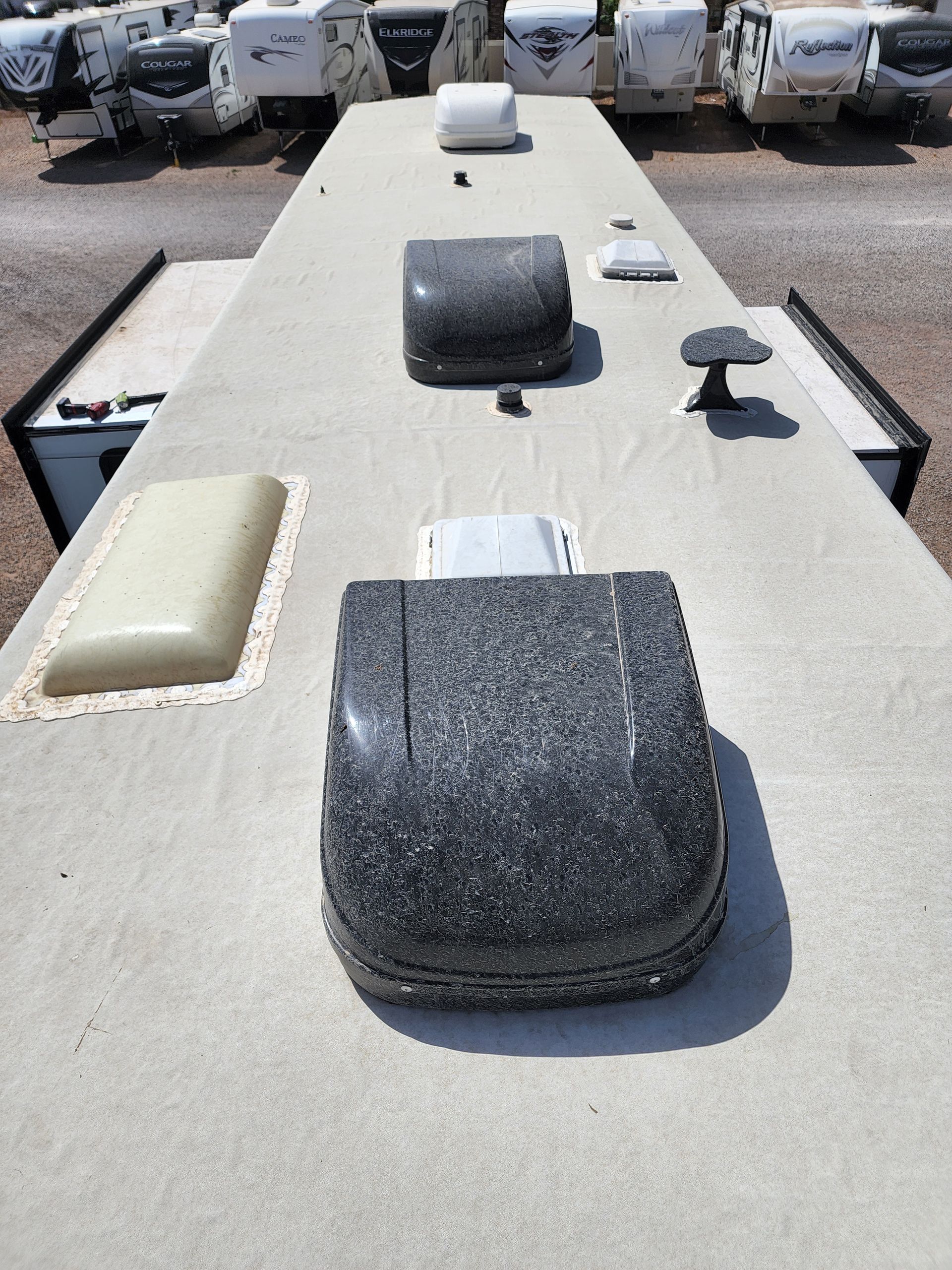 RV roof with various vents and skylights in a parking lot.
