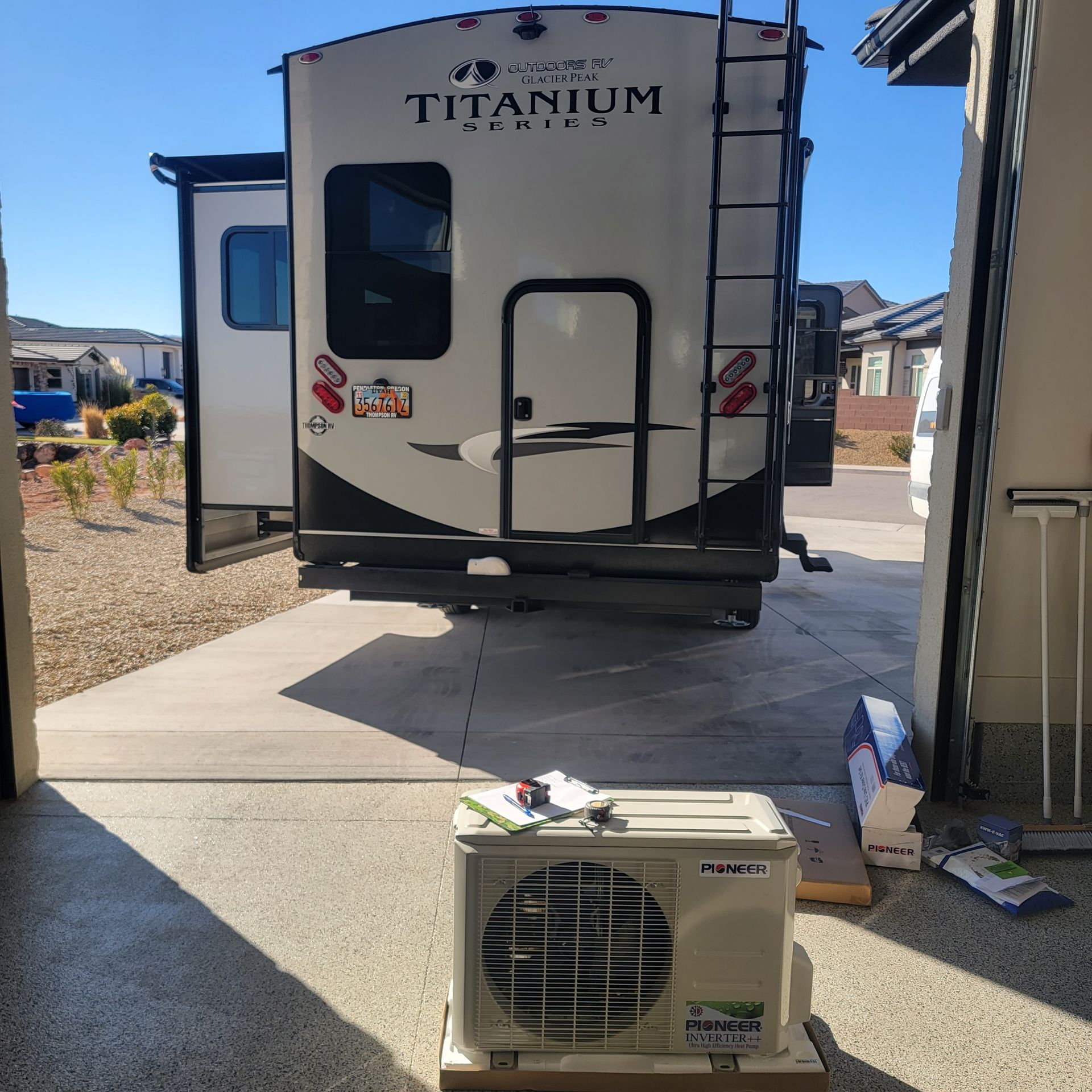 An RV parked in a driveway; a new air conditioning unit sits in front.