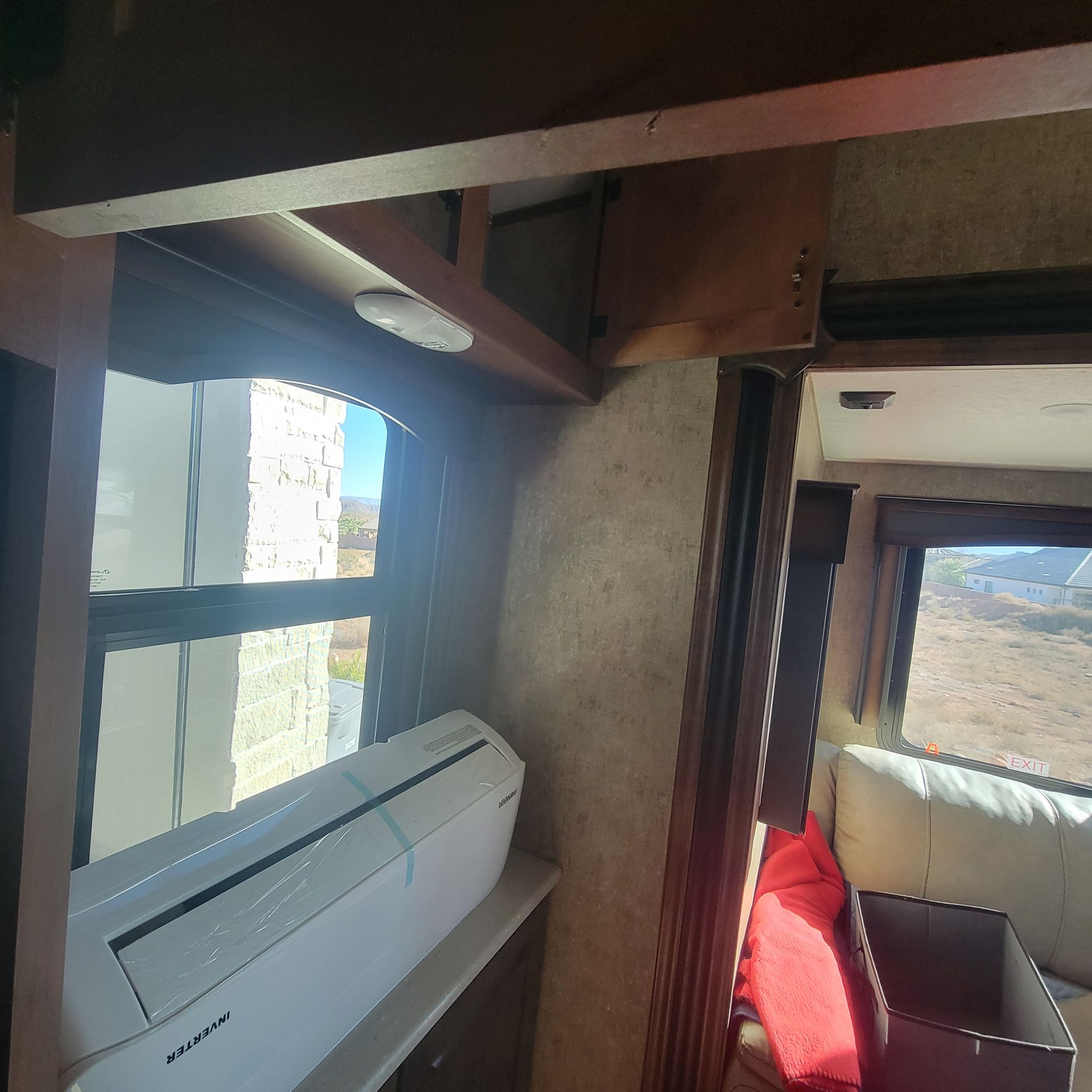Interior view of a recreational vehicle with a window and a wall-mounted air conditioner.