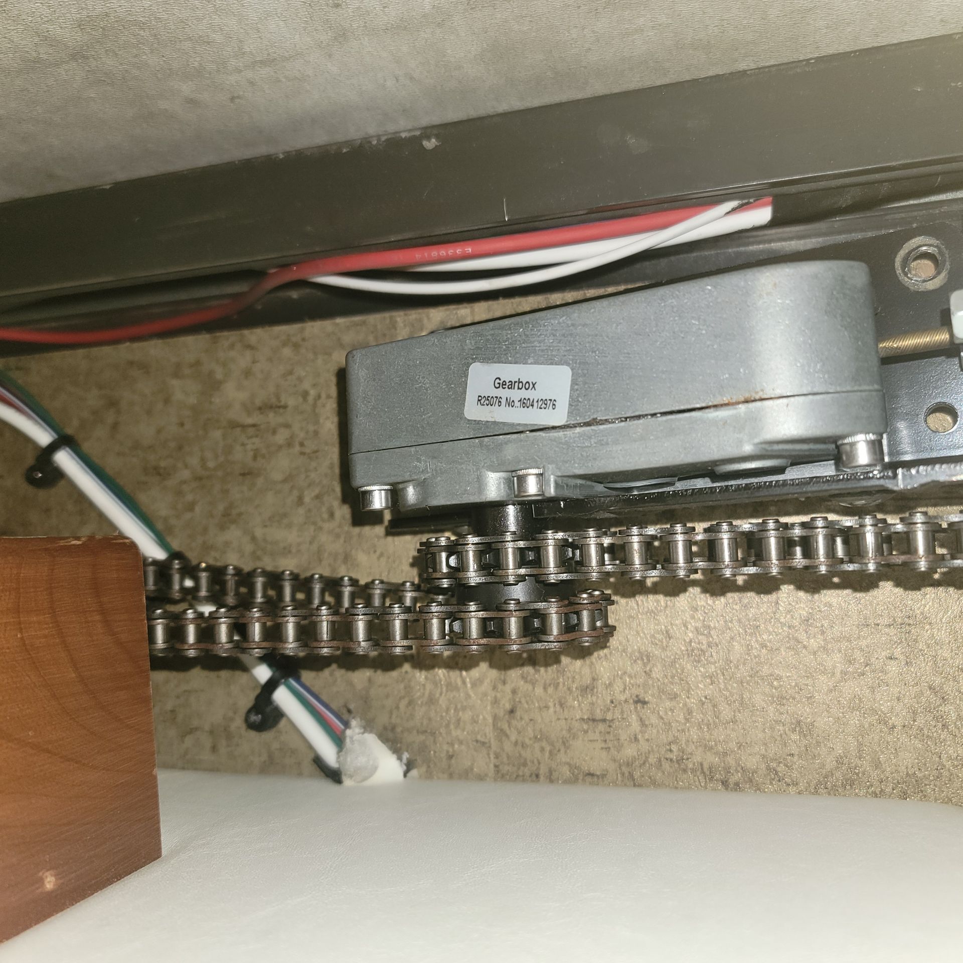 Motor and chain mechanism for a slide-out in an RV, with wiring and a wooden structure.