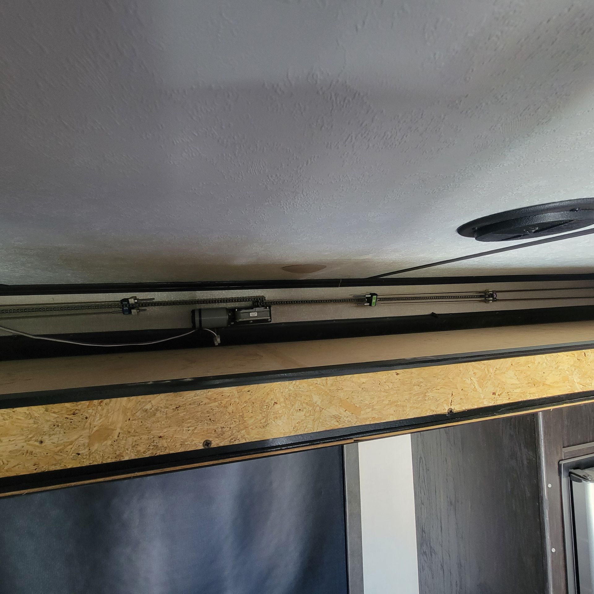 Black ceiling with wires and wooden beams. A dark wall and window are also visible.