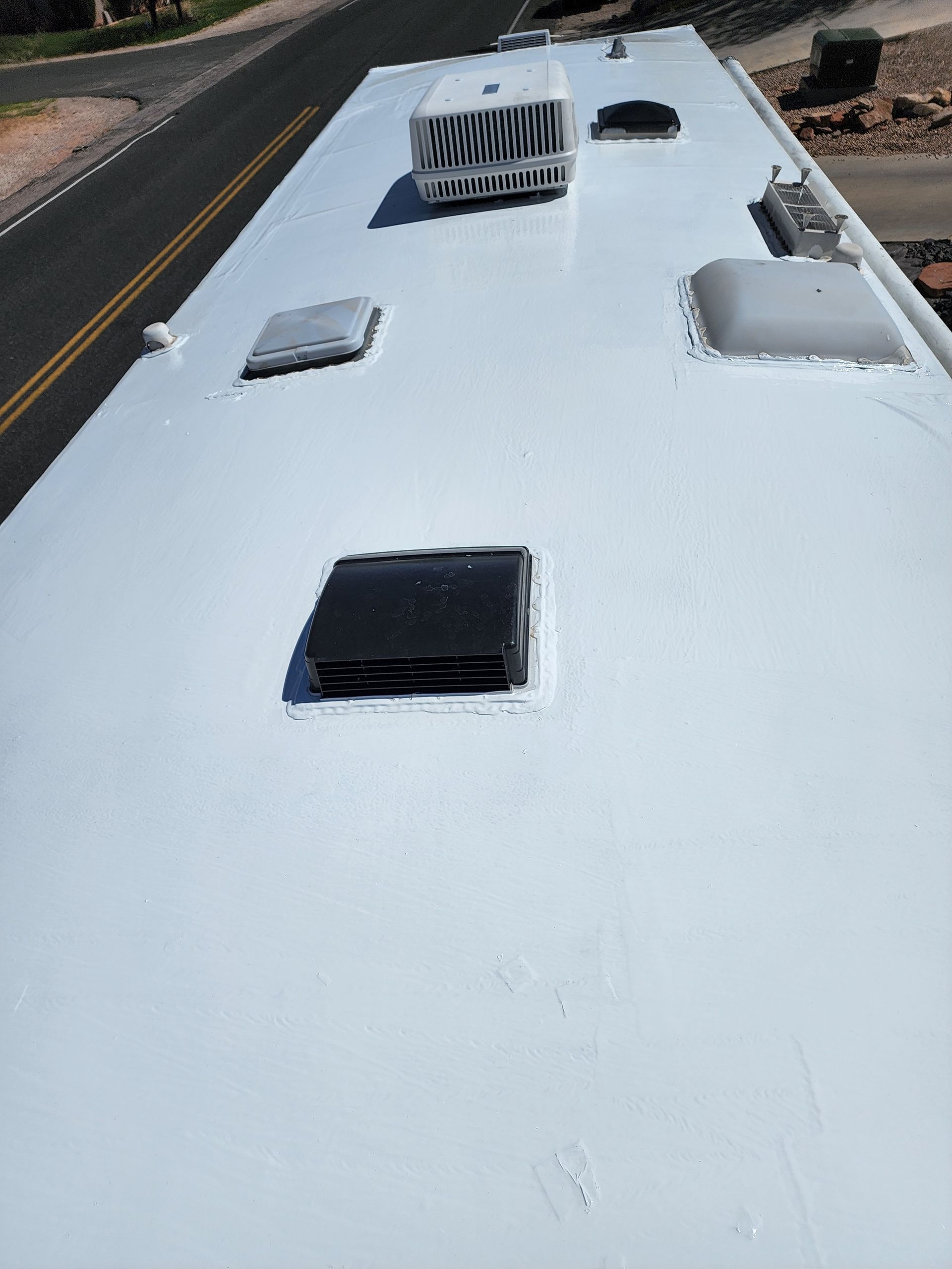 White RV roof with vents and air conditioning unit.