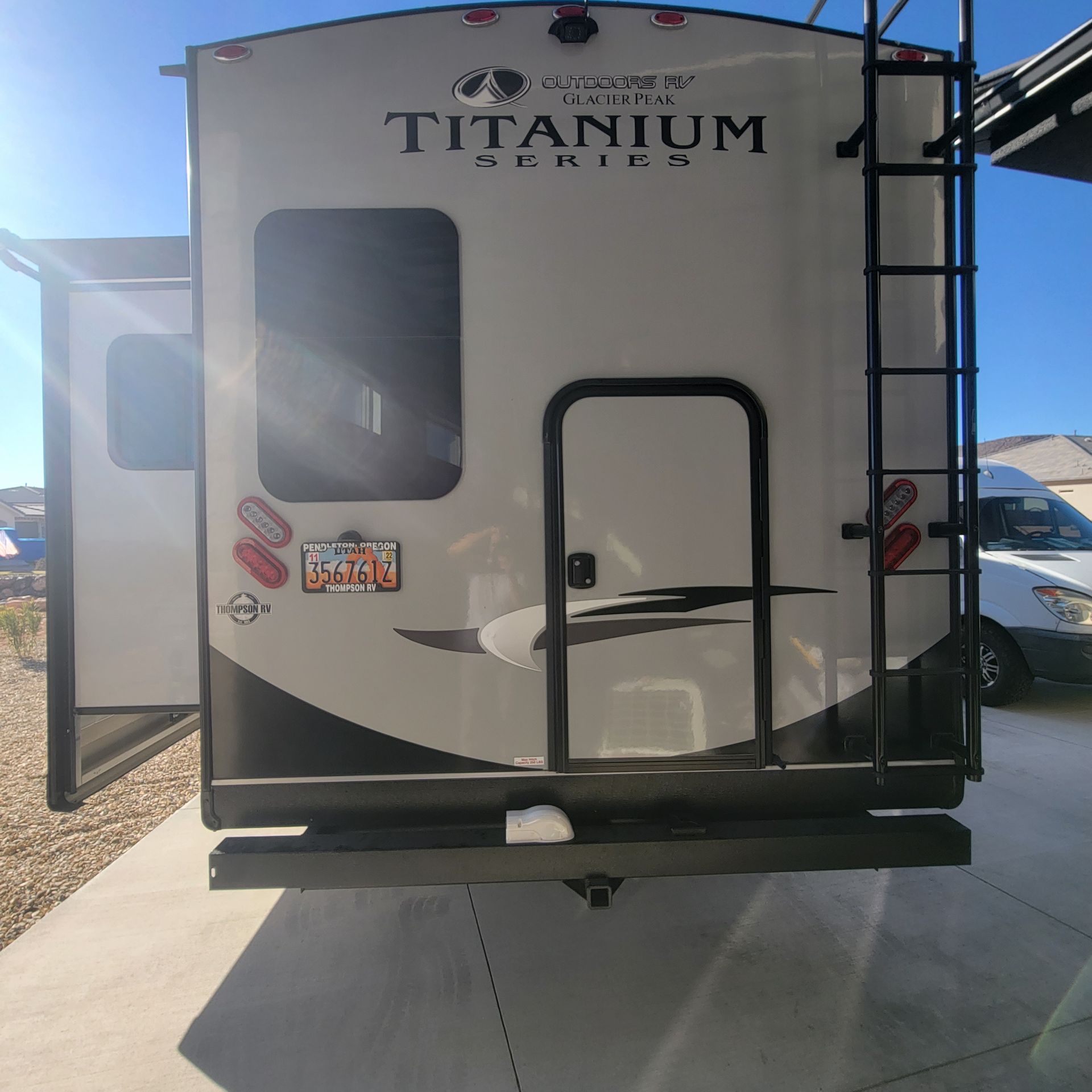 Rear view of an RV trailer with a black ladder, door, and 