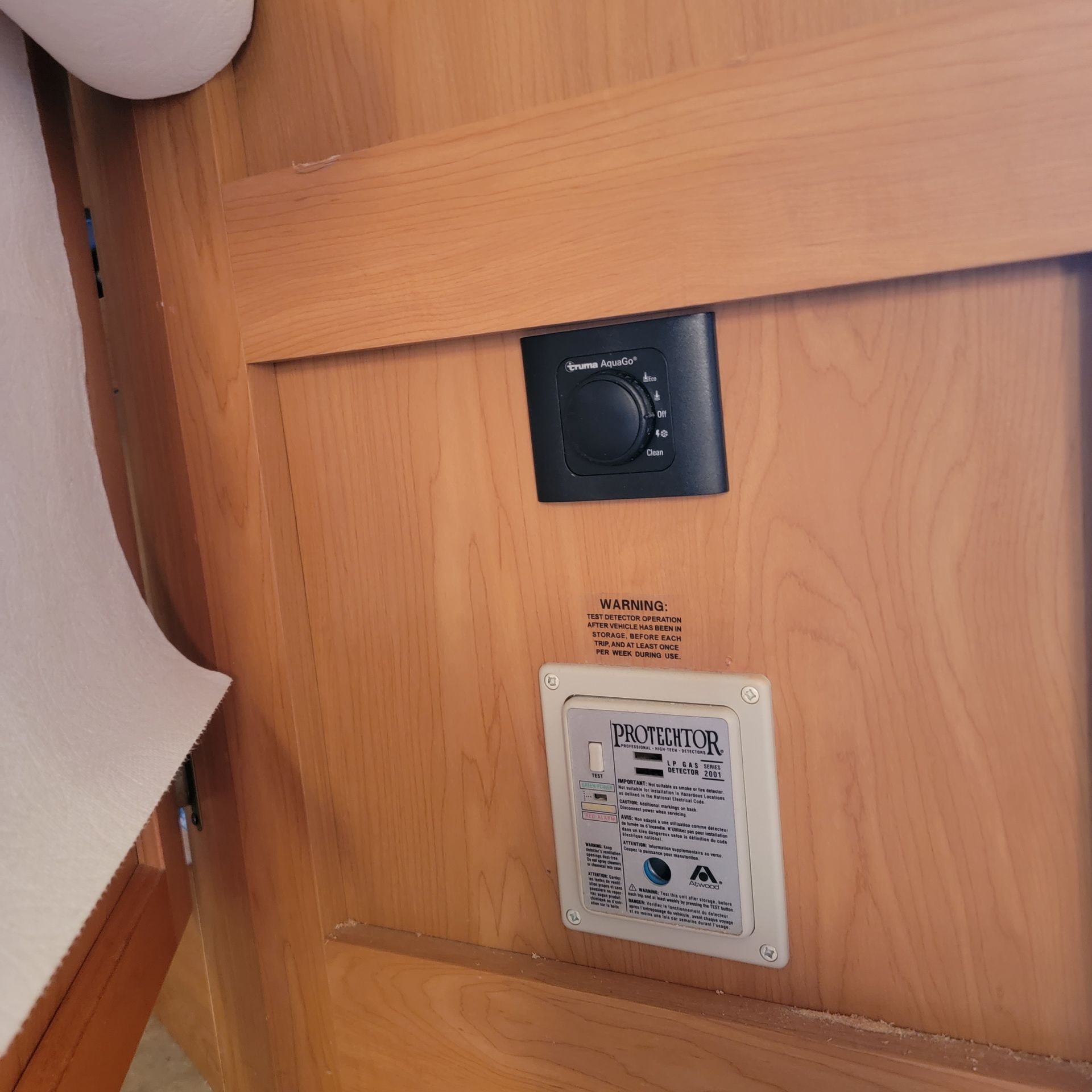 Wooden wall with a black control panel and a white panel with buttons and text.