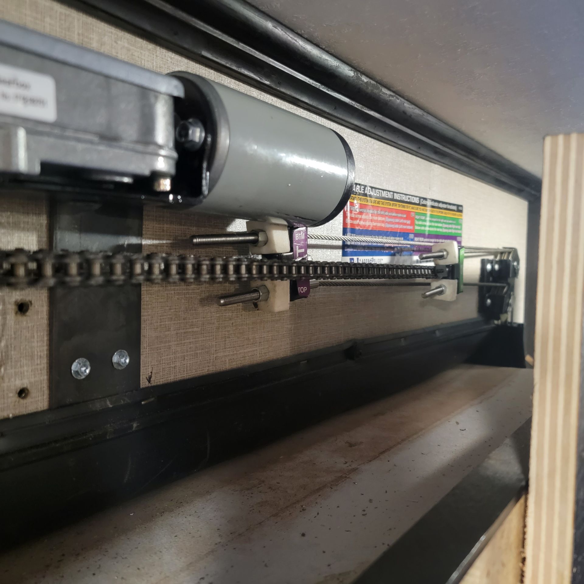 Motorized RV slide-out mechanism with chain and gears.