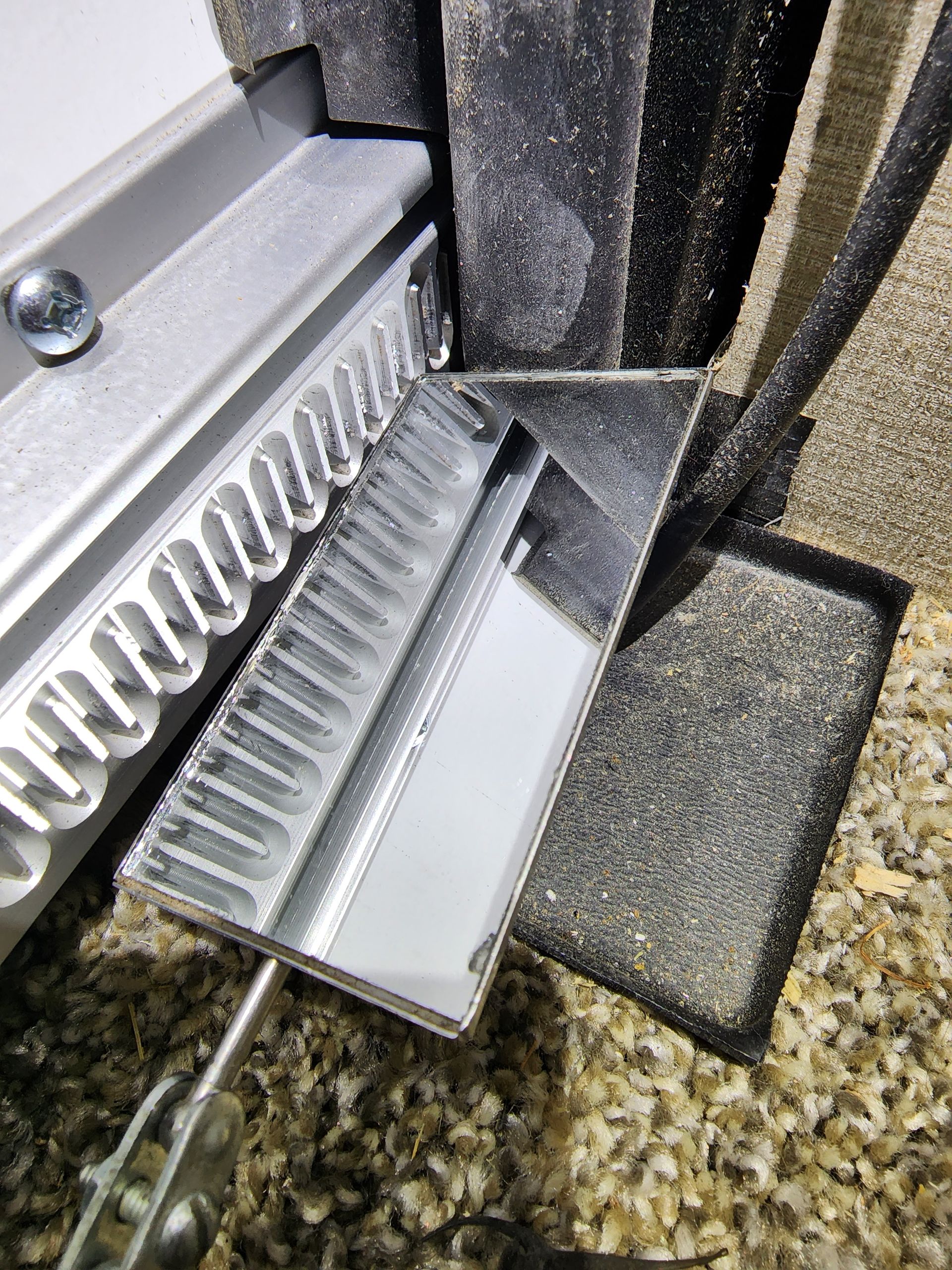 A mirrored scraper tool cleans debris from a vent system.