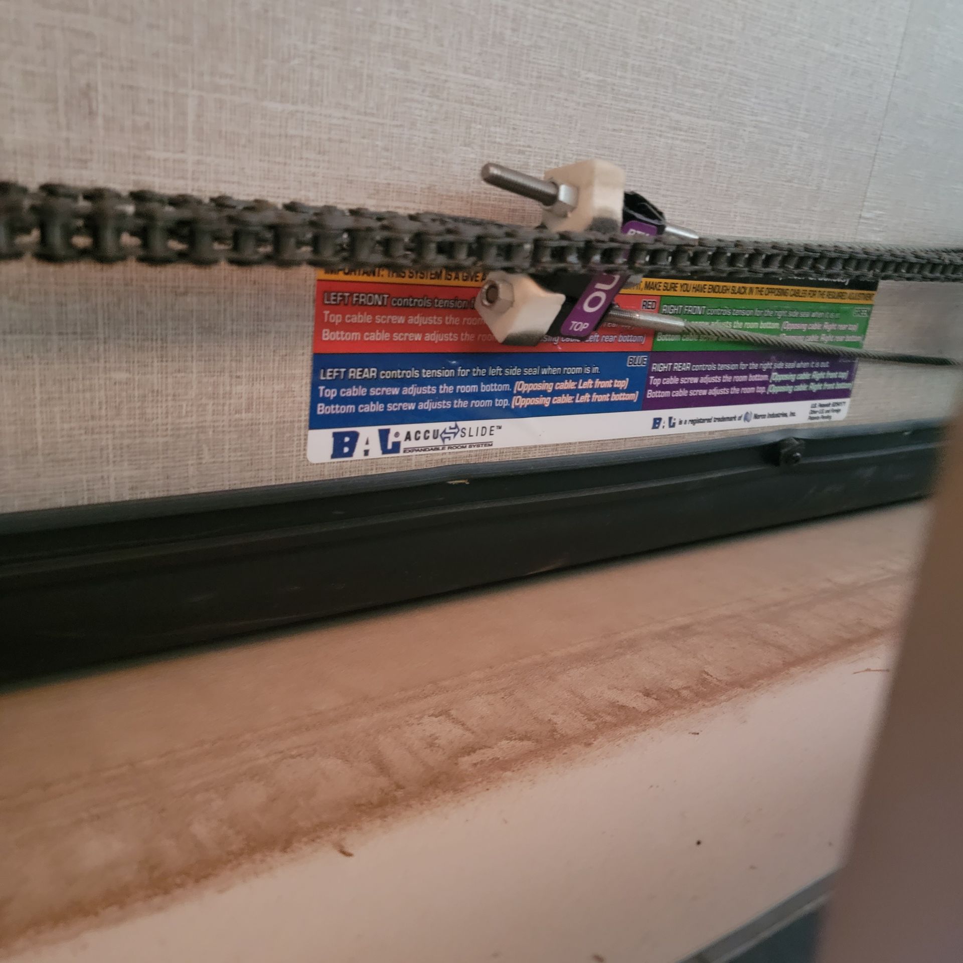Chain and brackets of a garage door opener. Black rail, dust, and a label are also visible.