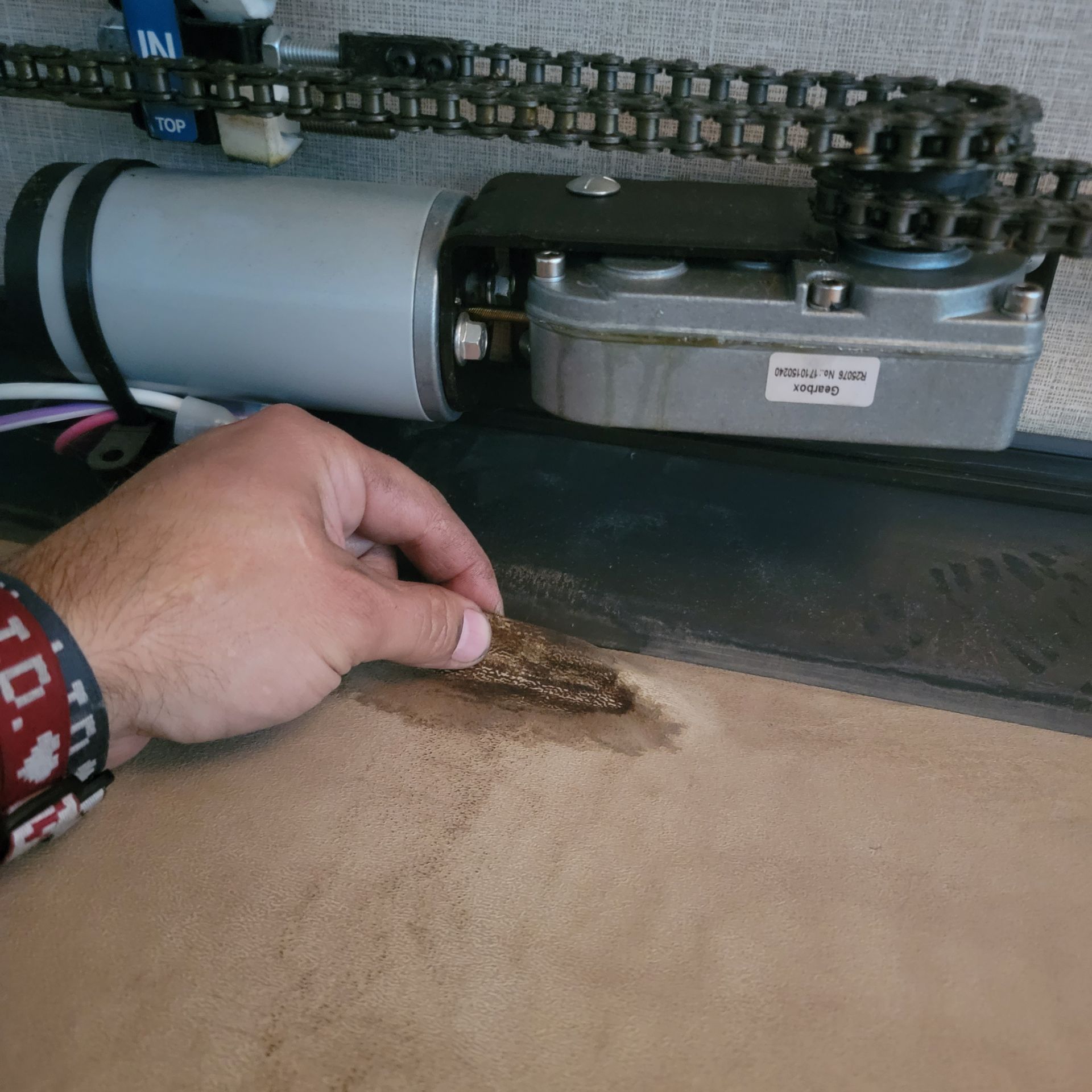 Hand holding debris near a motor and chain mechanism in a vehicle.