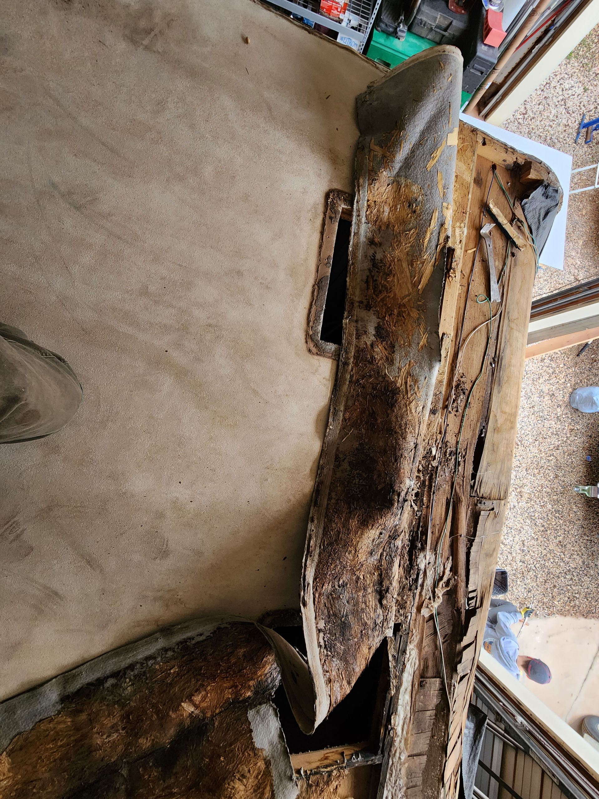 A damaged car headliner with deteriorated fabric and exposed structural material.