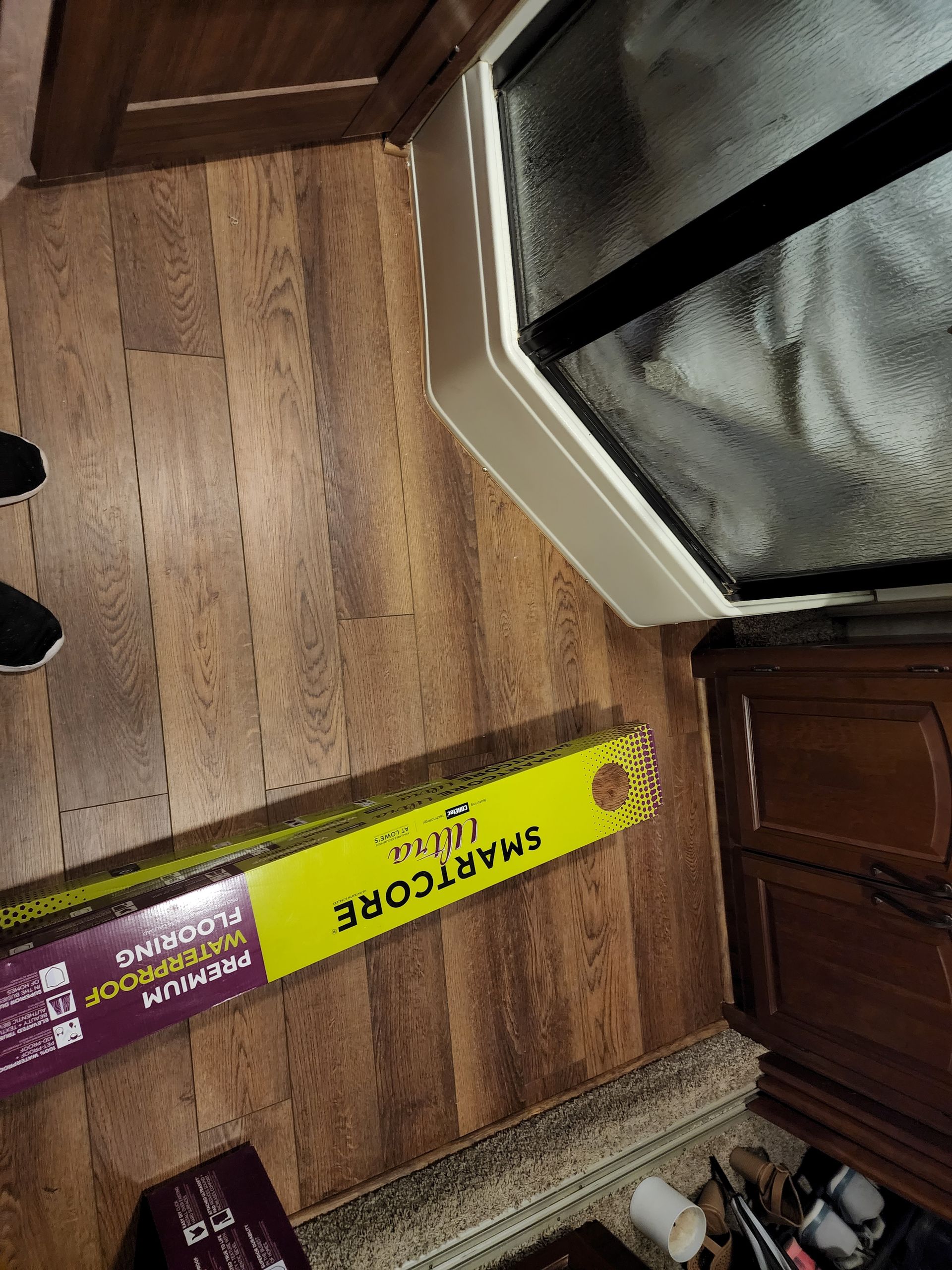 Bathroom floor with laminate flooring box, next to shower and dresser.