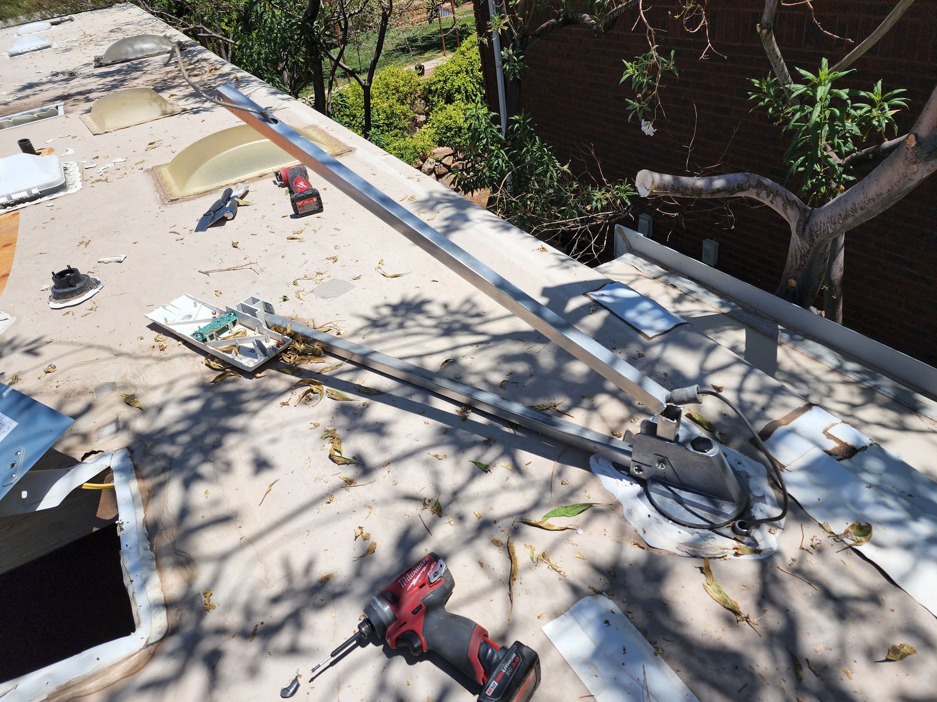 RV roof with repair in progress; metal bar, tools, and exposed roofing materials visible.