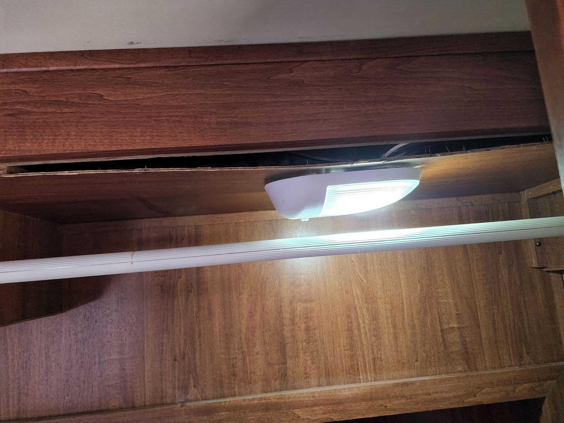 Inside a wooden cabinet, a white light illuminates the interior with a white rope-like object crossing in front.