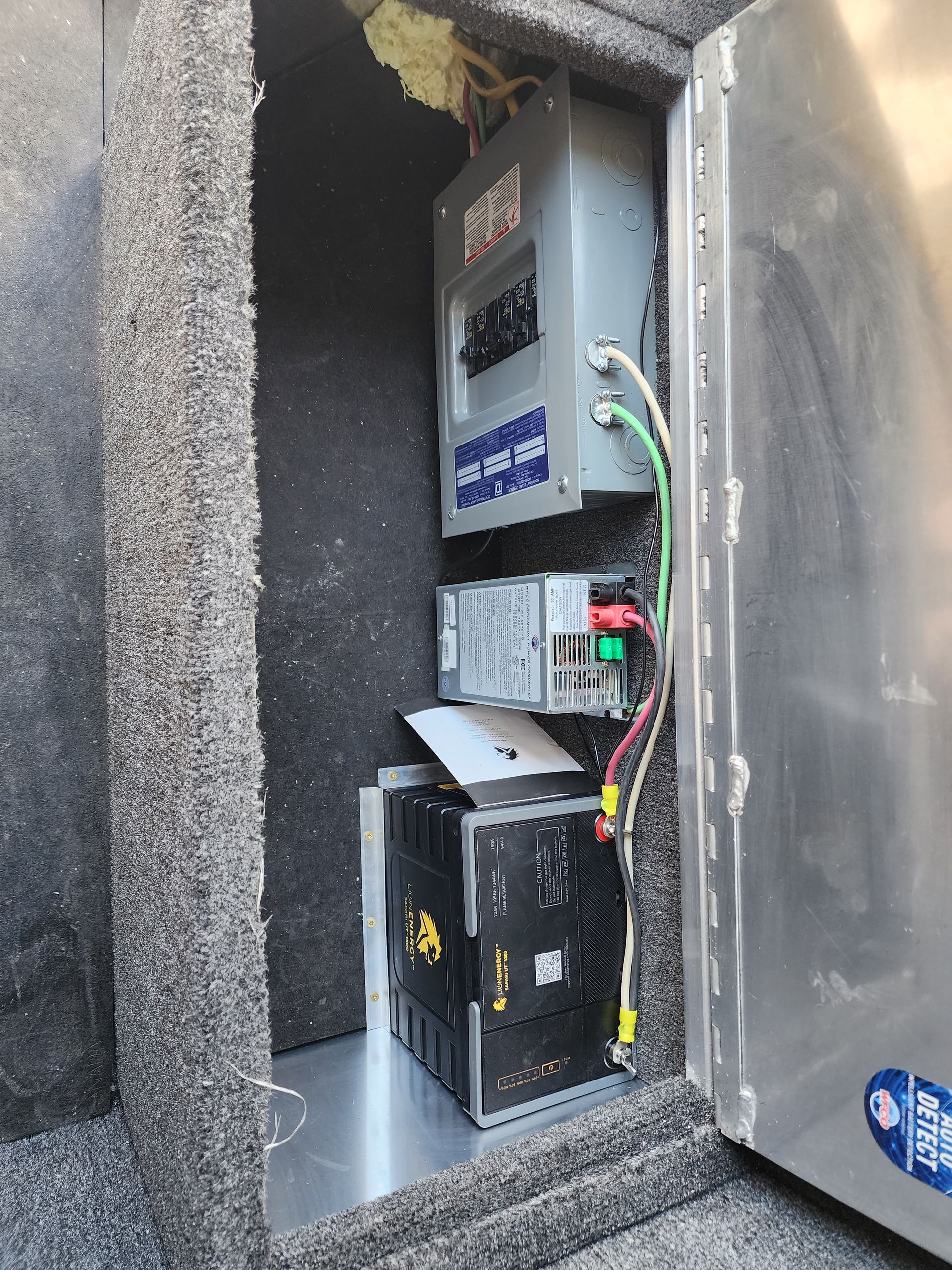 Electrical panel and battery compartment in a truck bed, featuring gray and black components.