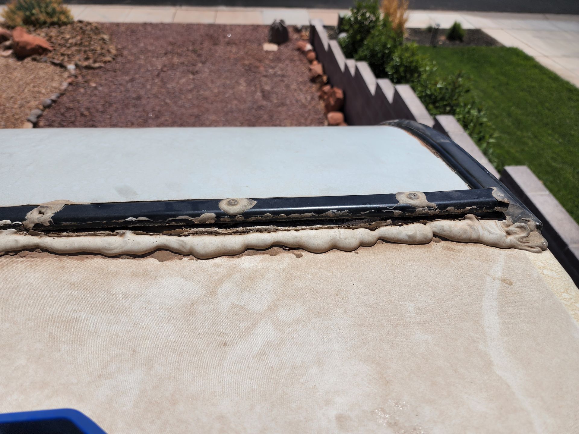 Close-up of a recreational vehicle roof with a window frame and sealant.