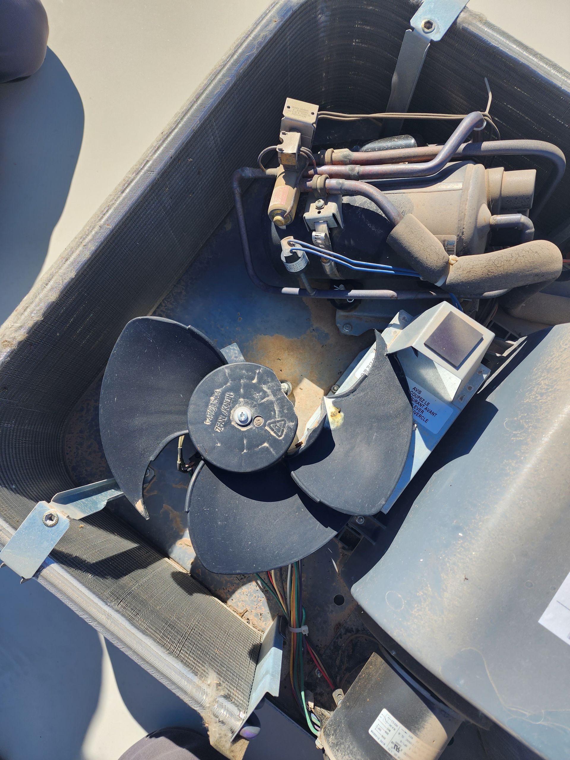 Damaged outdoor air conditioning unit with broken fan blades.