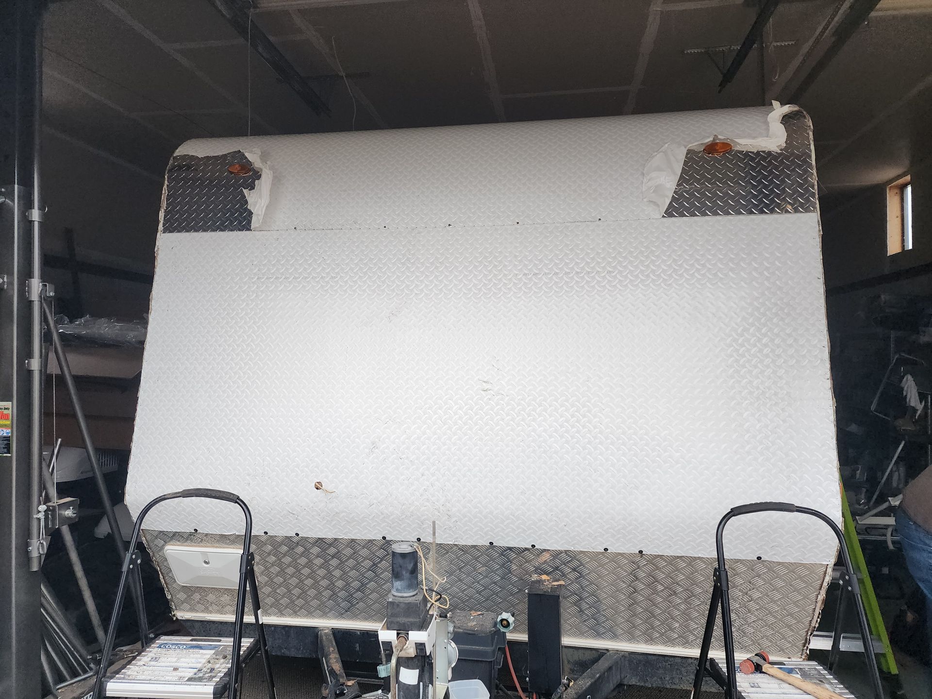Trailer front, diamond-plate and white paneling. Garage setting.