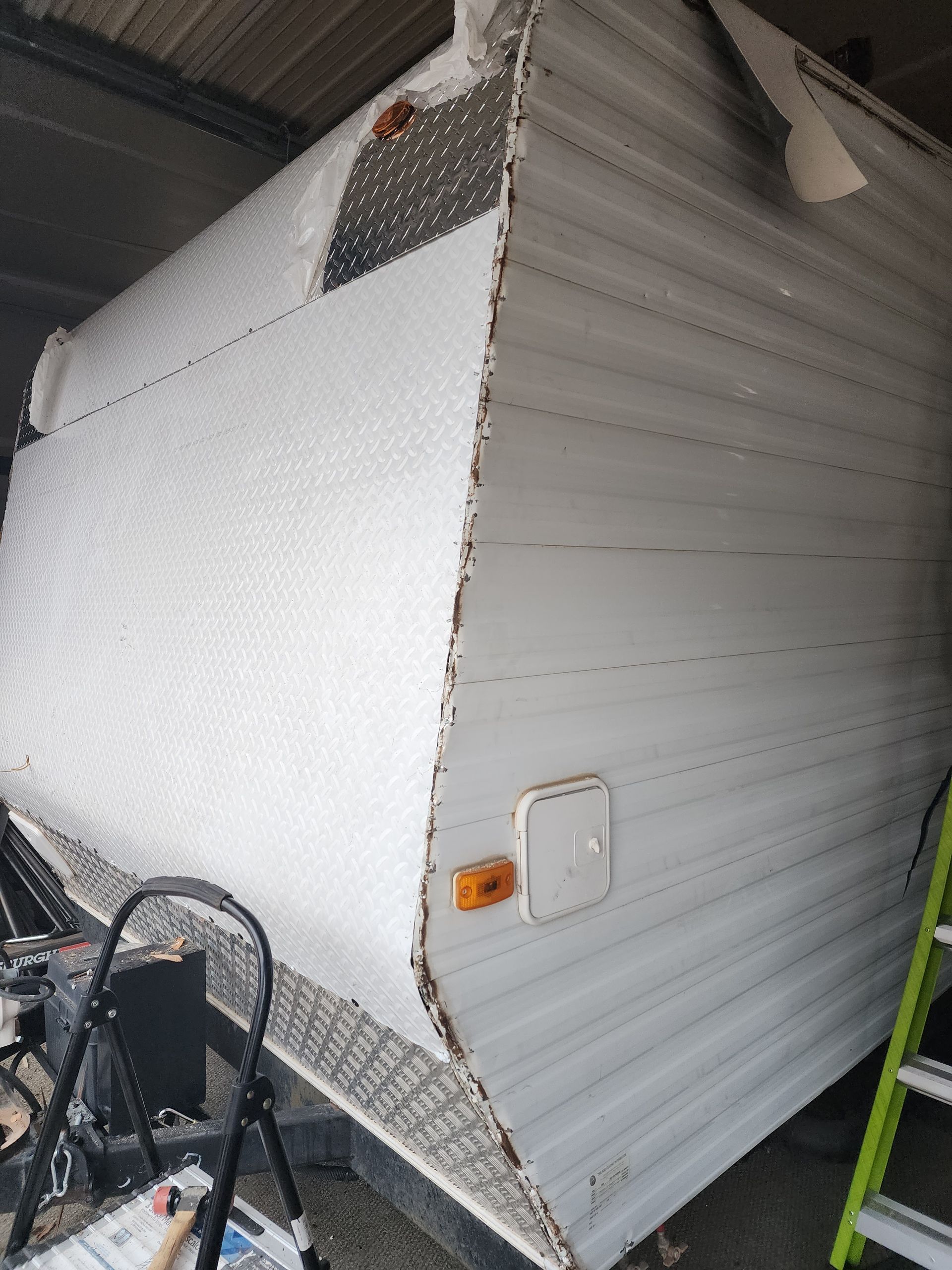 RV covered in bubble wrap, parked in a storage unit.