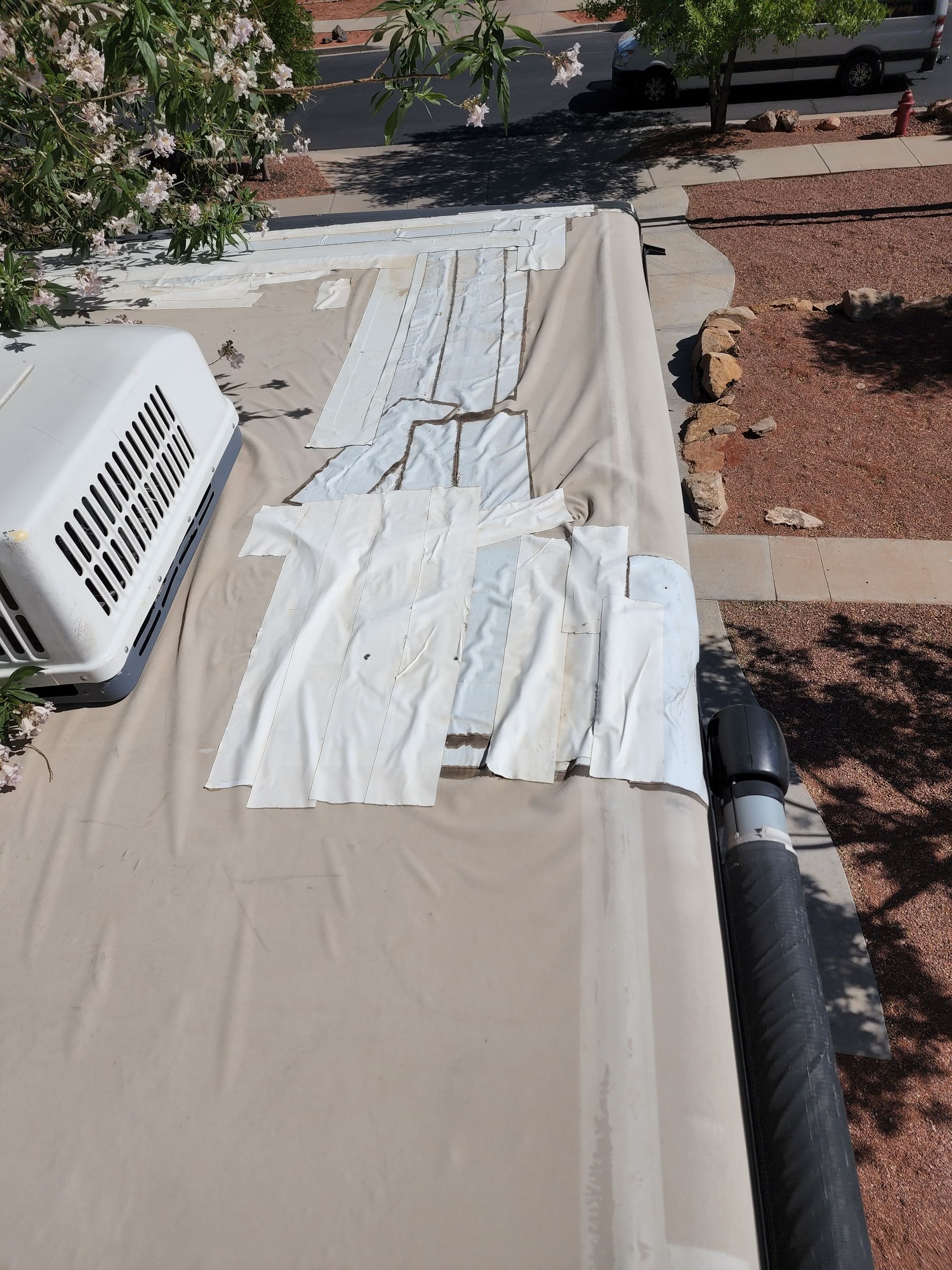RV roof with peeling white sealant and air conditioner unit.