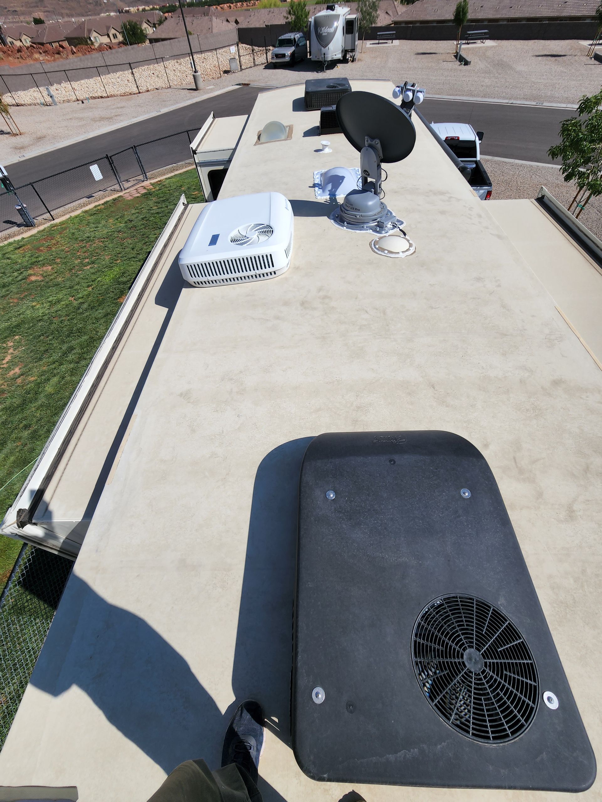 RV roof with equipment: satellite dish, air conditioner, and other components.