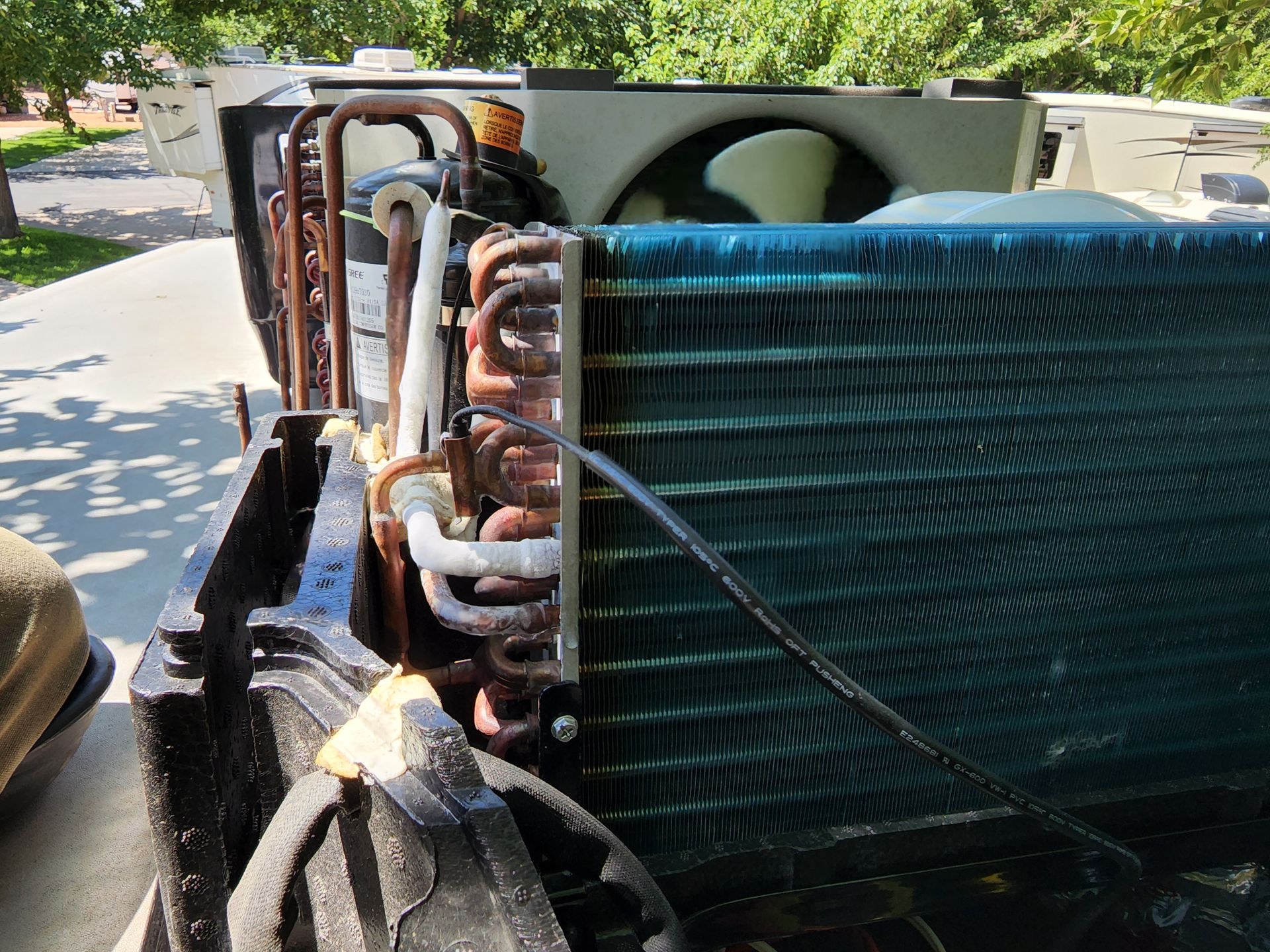 Open air conditioner unit, showing coils, fan, and components.